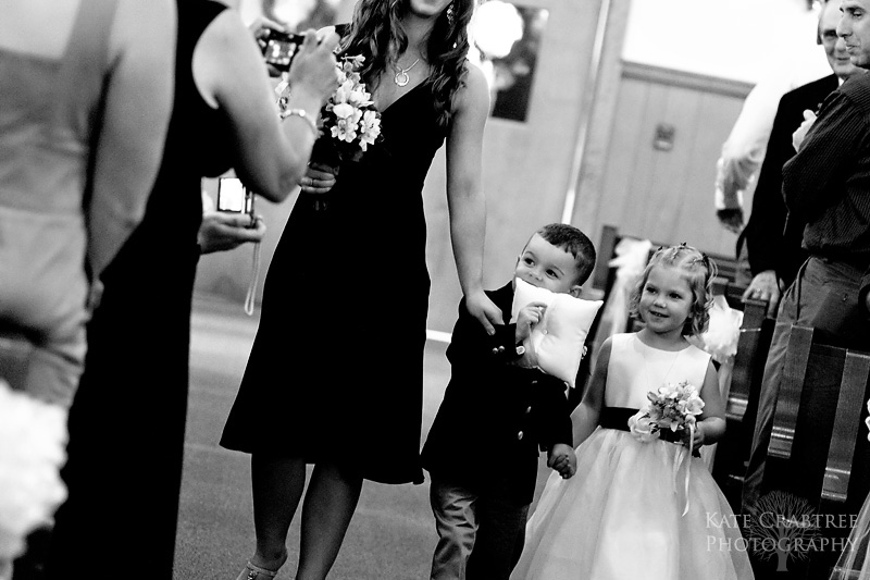 A bridesmaid walks the flower girl and ringbearer down the aisle at her wedding ceremony in Freeport Maine.