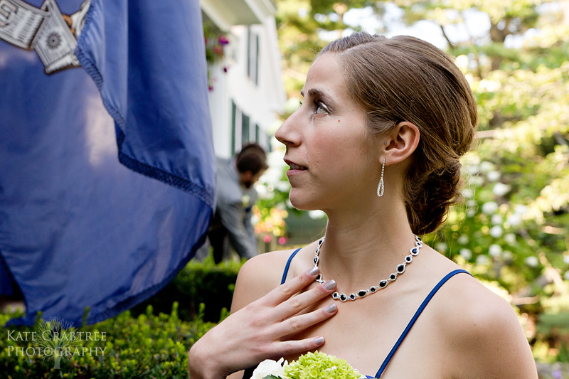 The maid of honor looks at the bride and groom as they take their formal portraits at Whitehall Inn