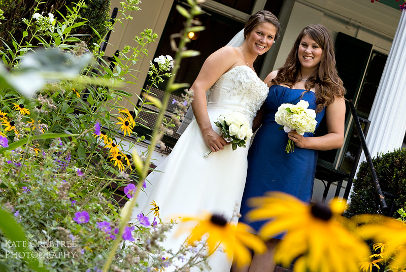The bride and maid of honor pose on the front porch of the Whitehall Inn