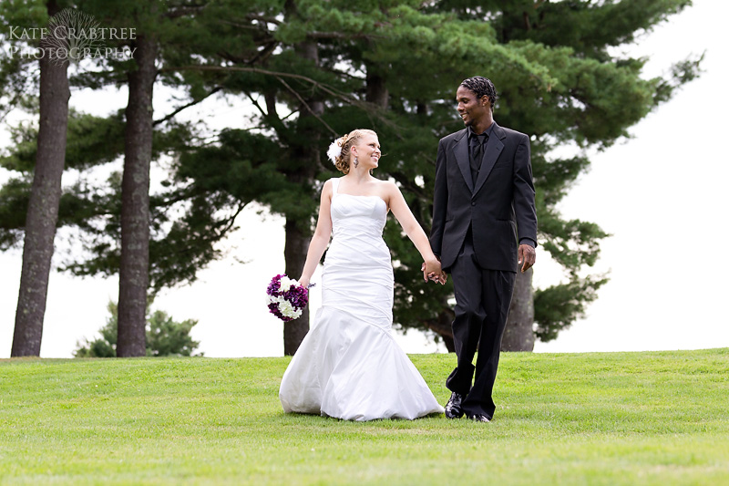 The bride and groom walk down to the lake after their wedding at the Lakeview Golf Course in Central Maine