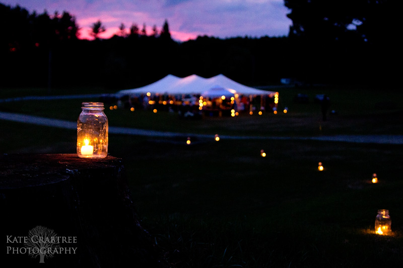 As the sun sets, candles in mason jars light the way to the tented wedding reception at the Lakeview Golf Course in Central Maine