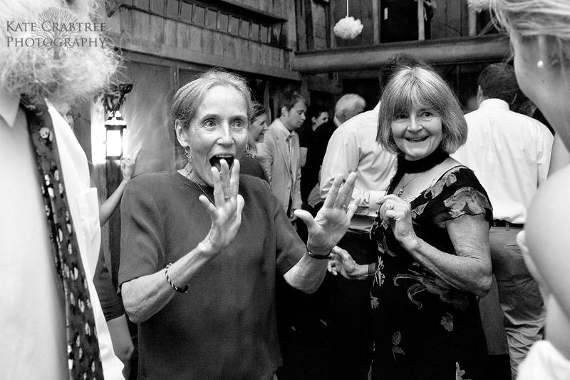 The mothers of the bride and groom chat animatedly during a rustic coastal Maine wedding