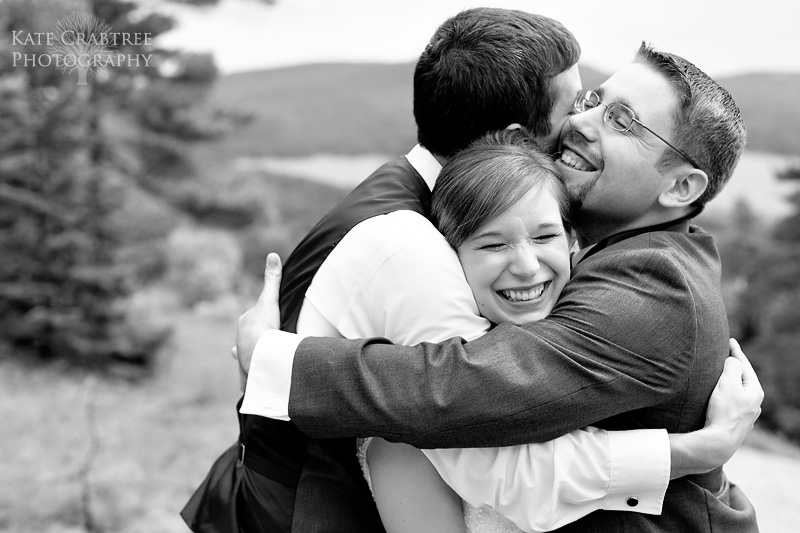 The best man and the groom hug the bride during their Lucerne Inn wedding in Dedham Maine