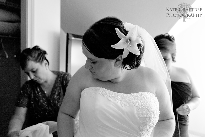 The mother of the bride helps the bride get into her dress at her western Maine wedding