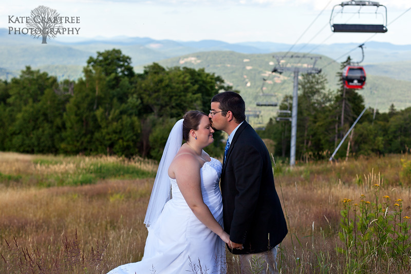The groom kisses the bride's forehead during their portrait session at sunday river in western maine