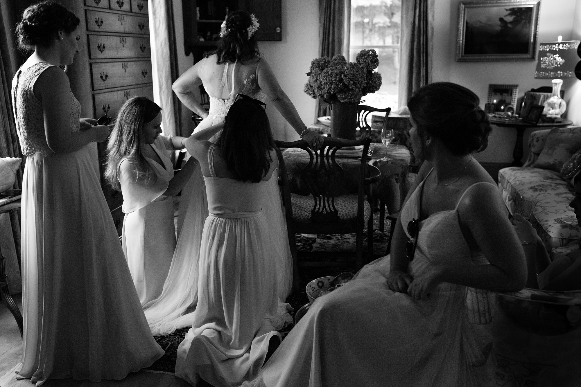 The bridesmaids help the bride bustle her wedding dress