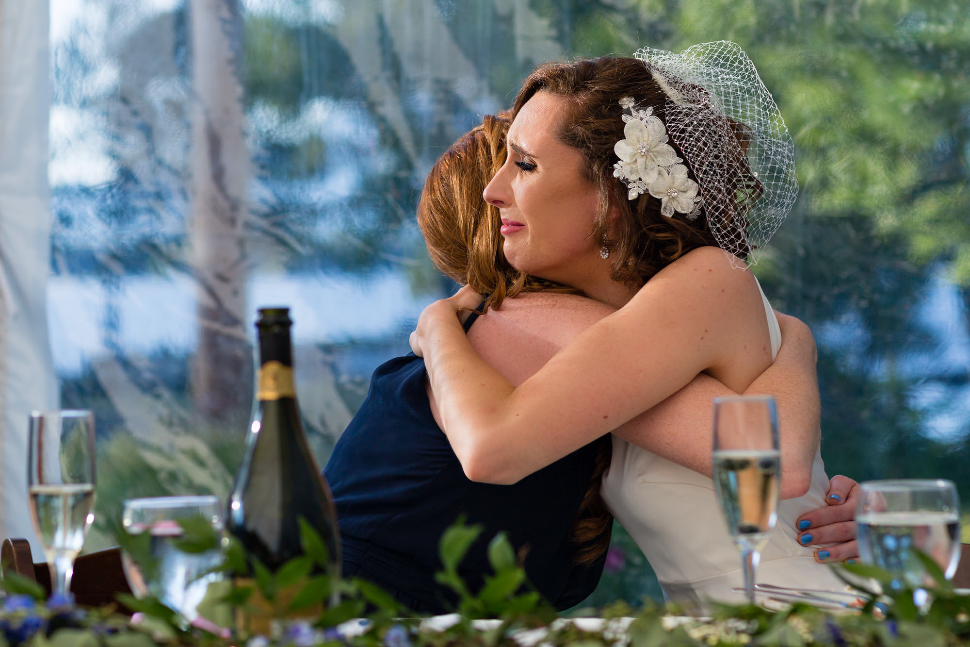 A documentary wedding photo of a bride hugging her maid of honor.
