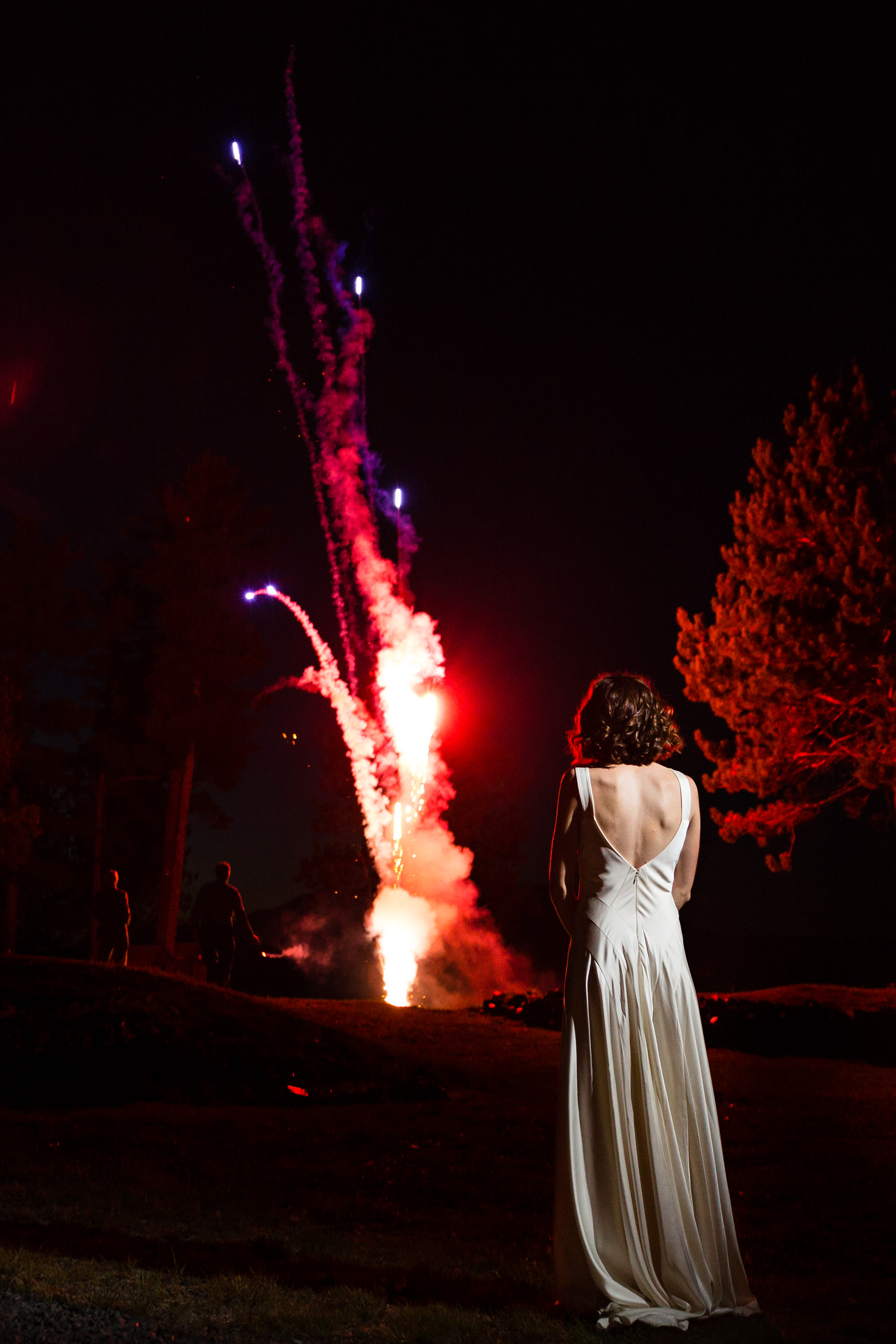 A bride watches a fireworks show at the end of her wedding day at the New England Outdoor Center