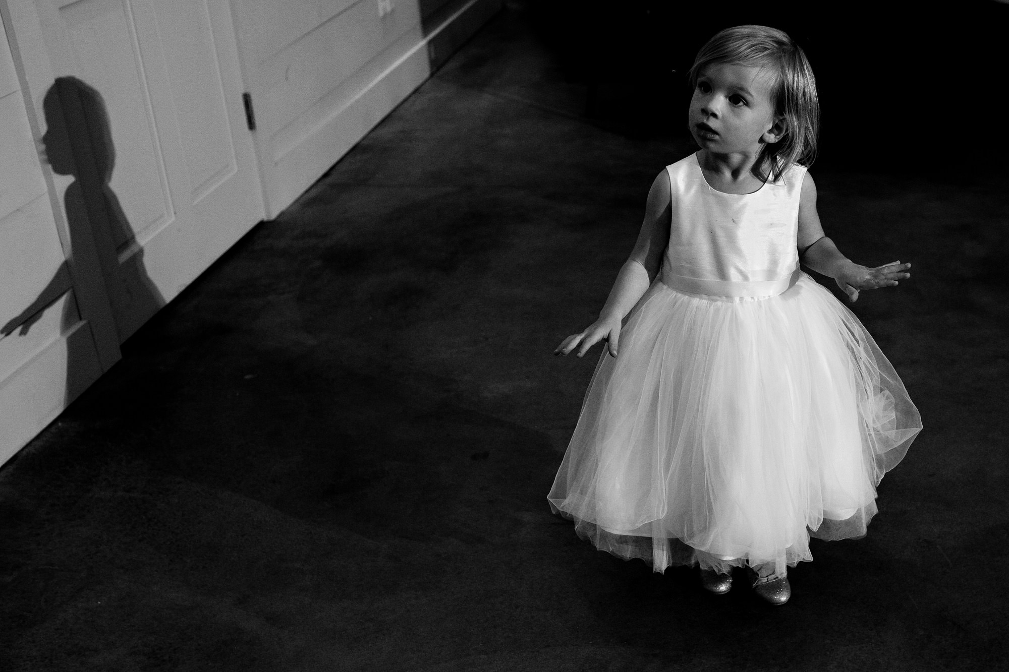 A dramatic black and white of a flower girl at a wedding reception.