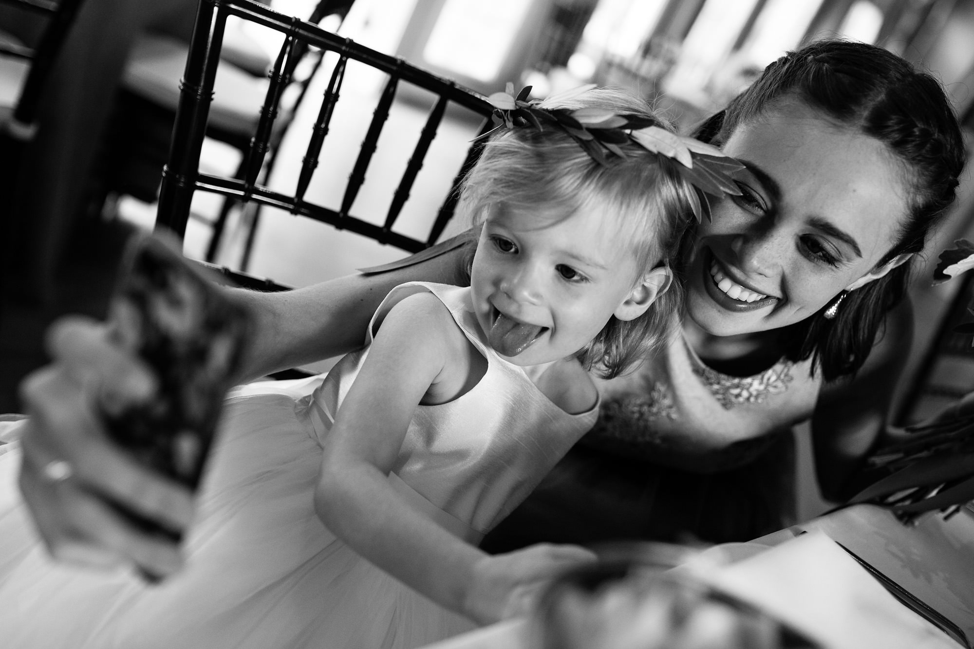 A bridesmaid and a little girl play with a cellphone at a Kennebunkport wedding.