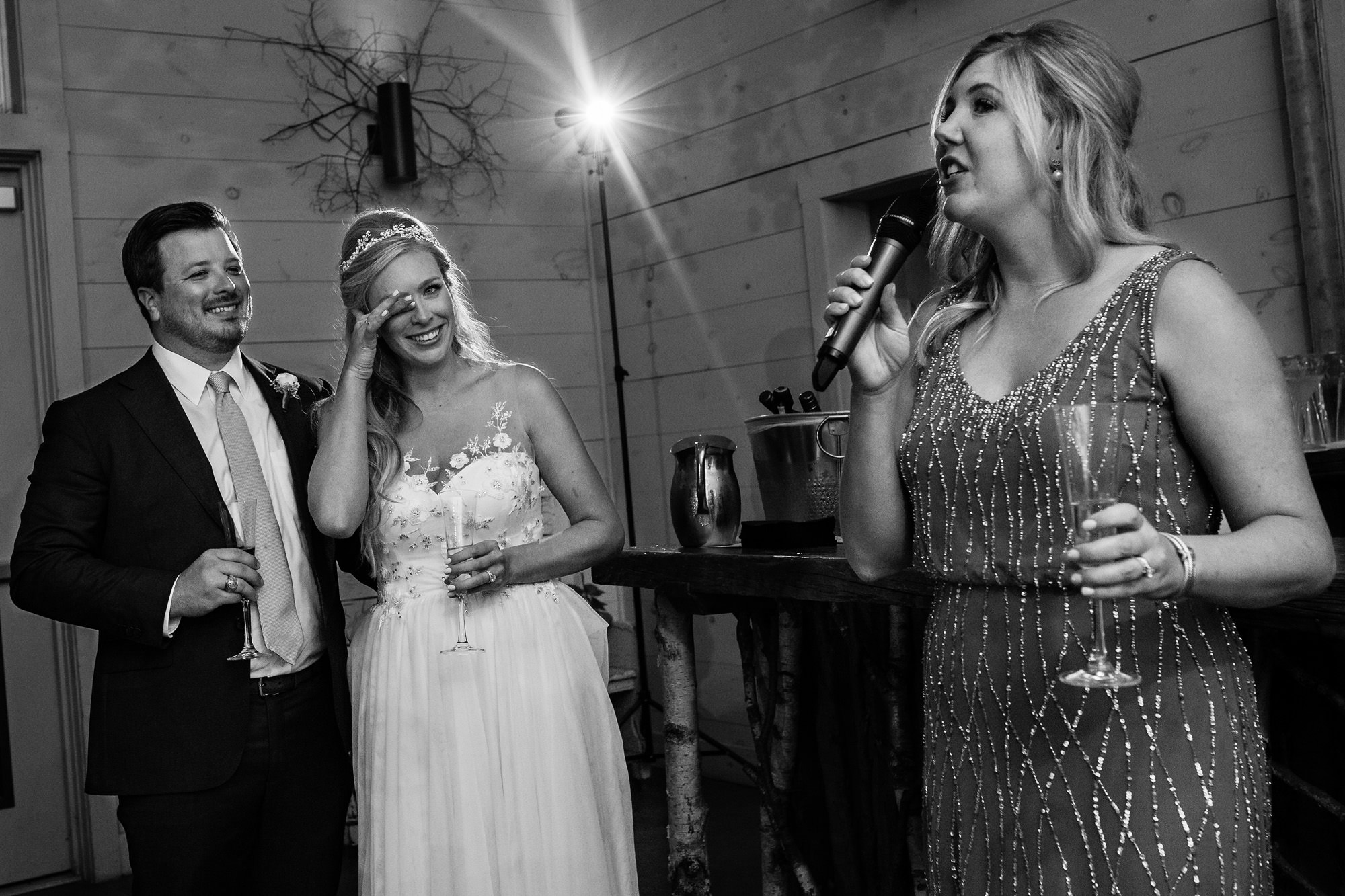 A bride and groom enjoy a toast by the maid of honor at their Maine wedding.