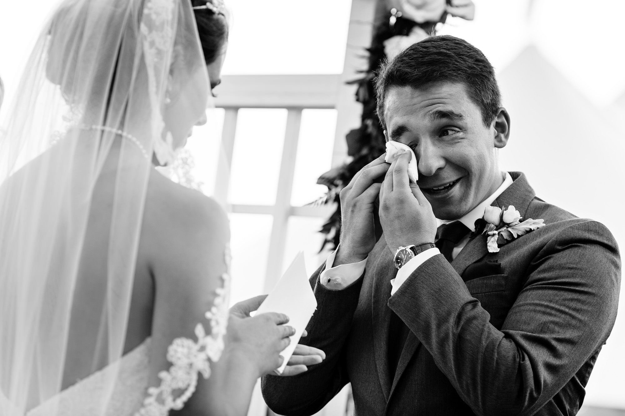 A groom cries as his bride reads her vows at their coastal Maine wedding.
