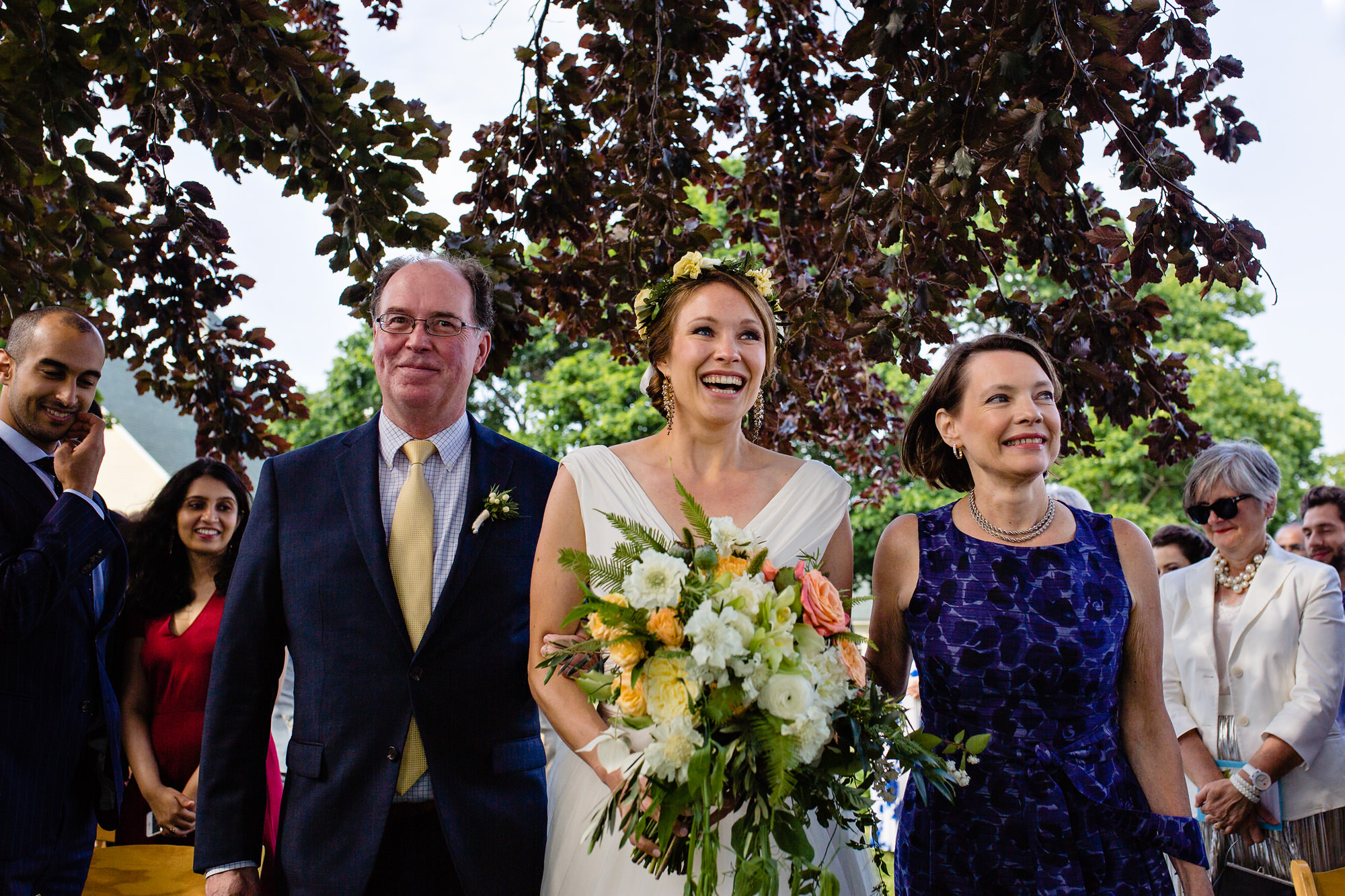 A bride walks down the aisle with her parents at her Laudholm Farm wedding in Wells Maine