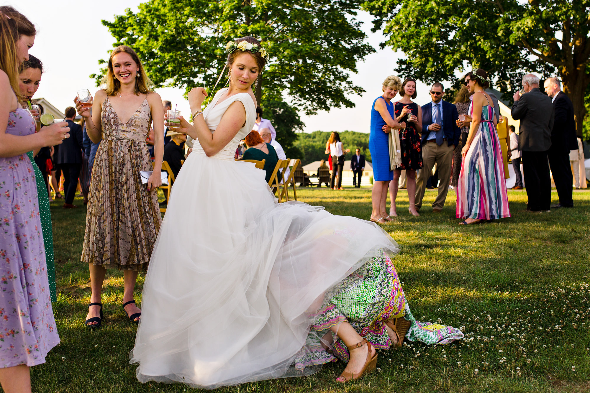 A friend attempts to help with the bride's dress in a comical moment at Laudholm Farm