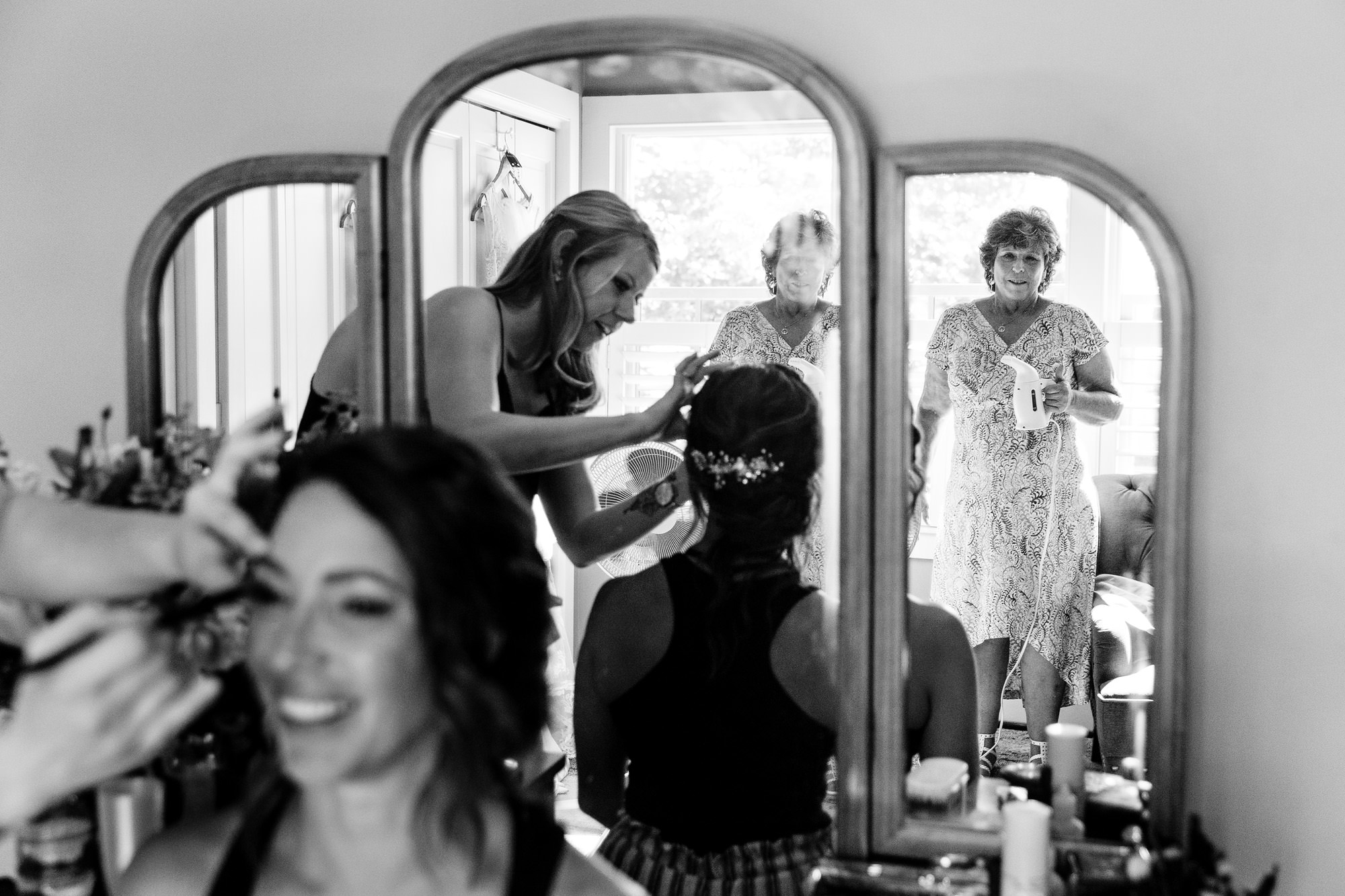 The mother of the bride looks at the bride while she gets ready for her wedding in Maine