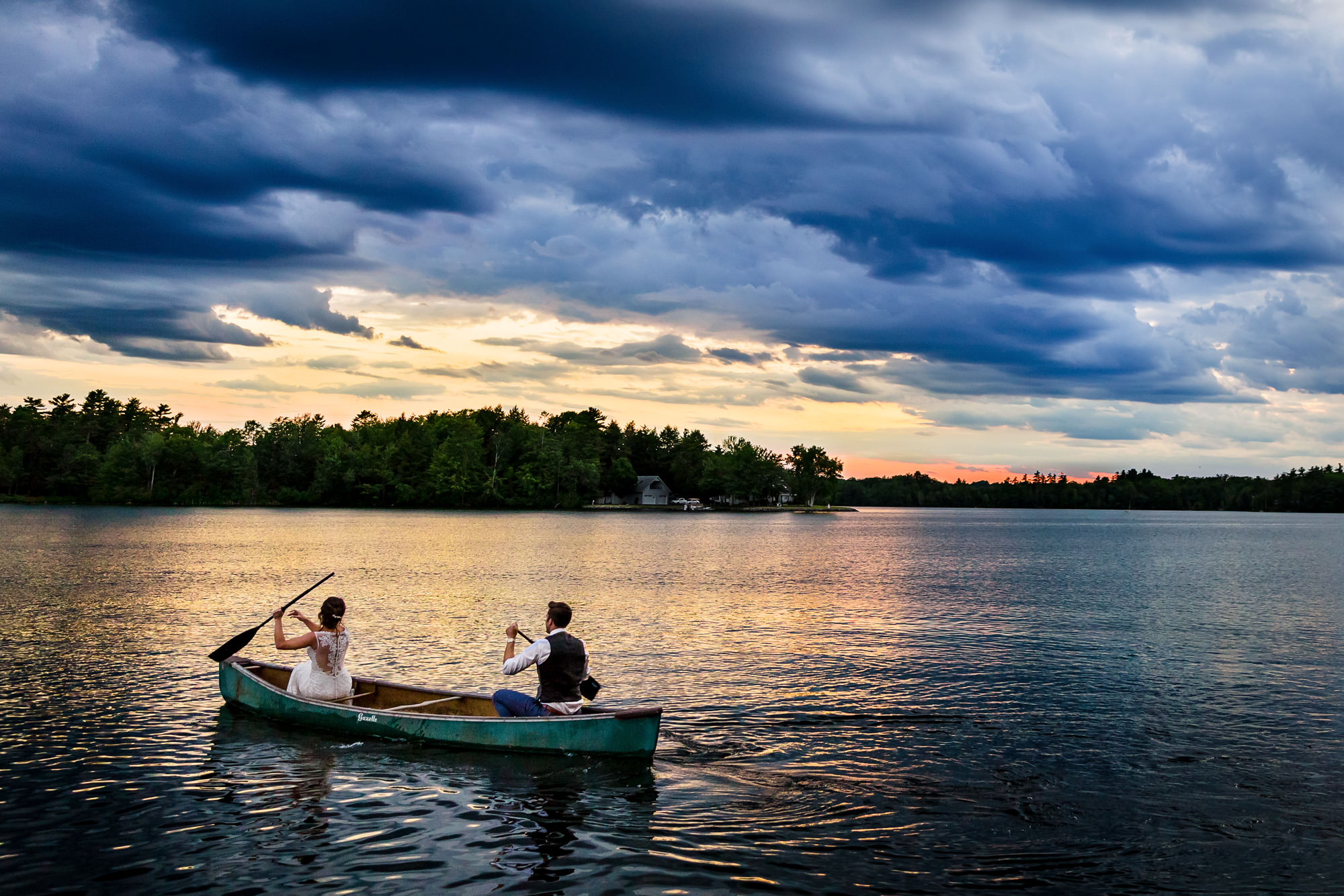A bride and groom canoe at sunset on Cobbosseecontee lake
