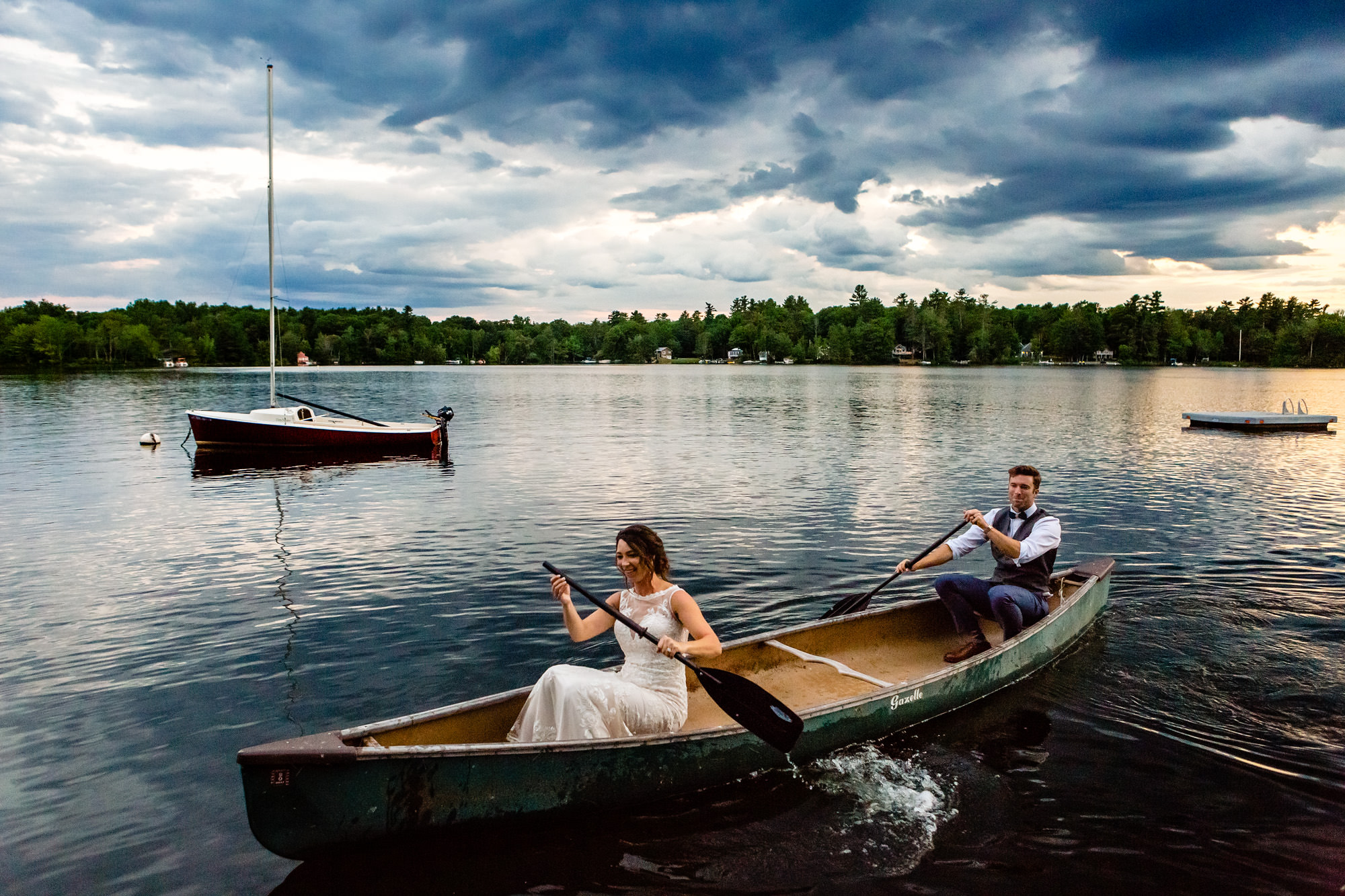 A bride and groom canoe at sunset on Cobbosseecontee lake