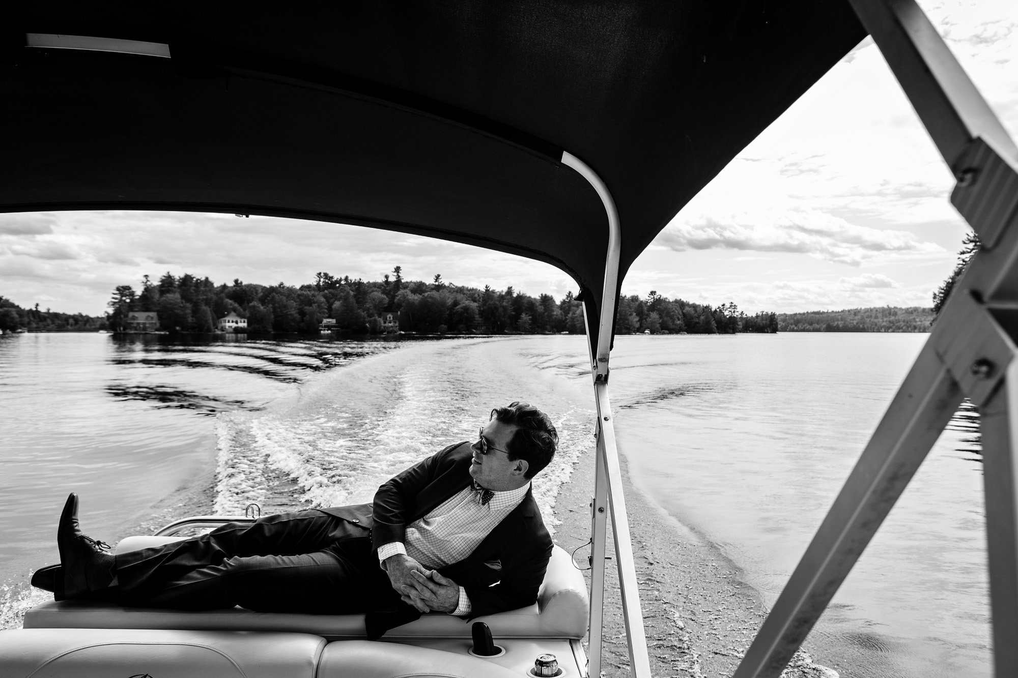 A groom boats to his lakeside Maine wedding