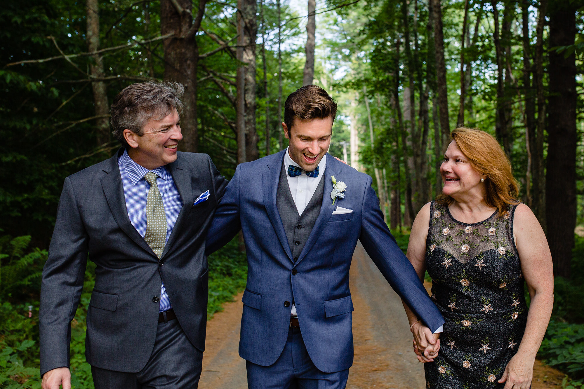 A groom holds his parents' hands at his wedding.