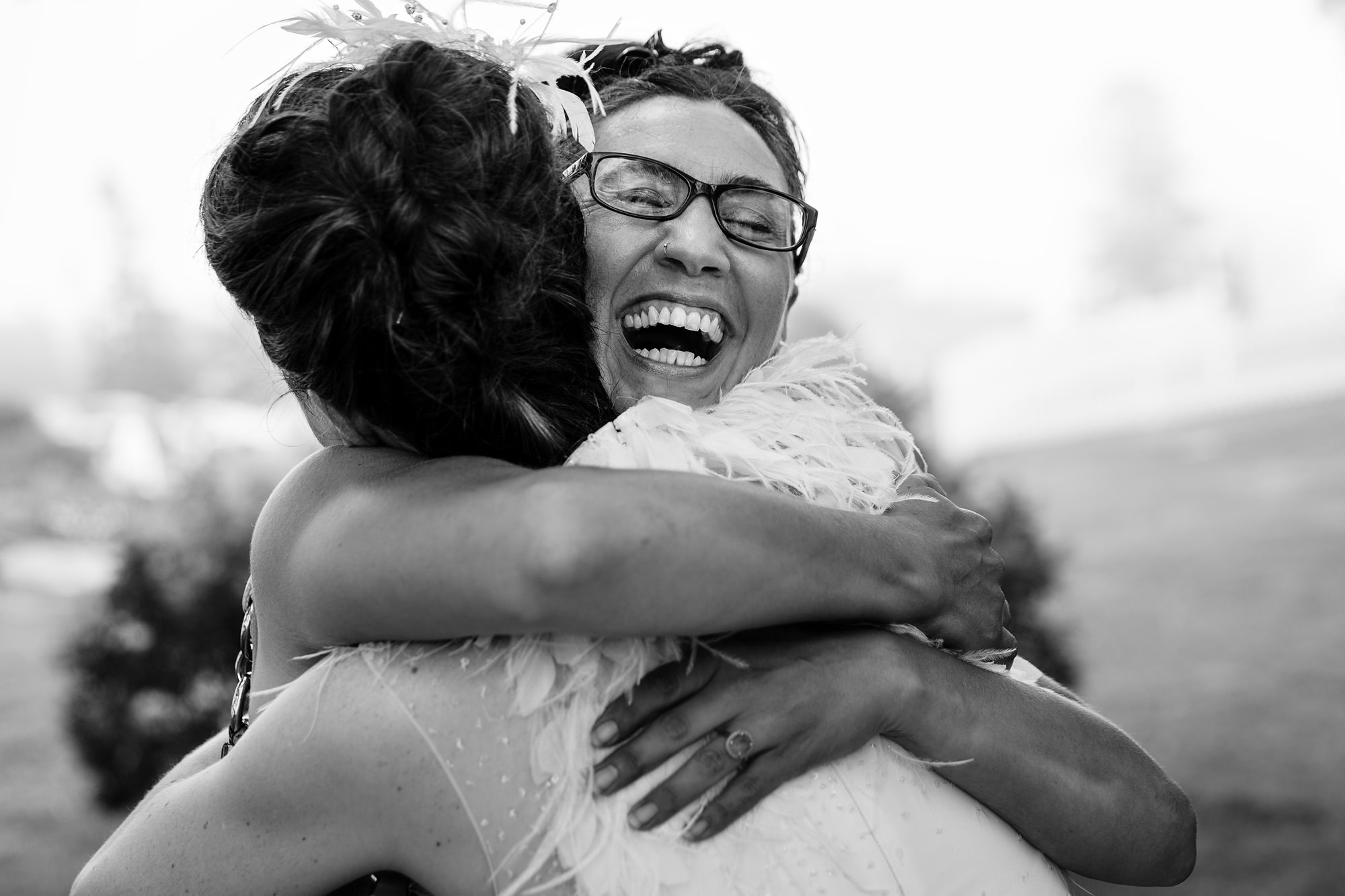 A candid photo of a friend excitedly hugging the bride at a wedding in Maine.