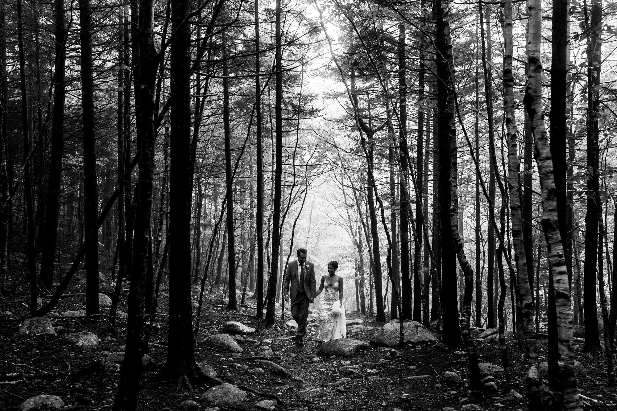 A couple walks through the woods during their Acadia elopement.