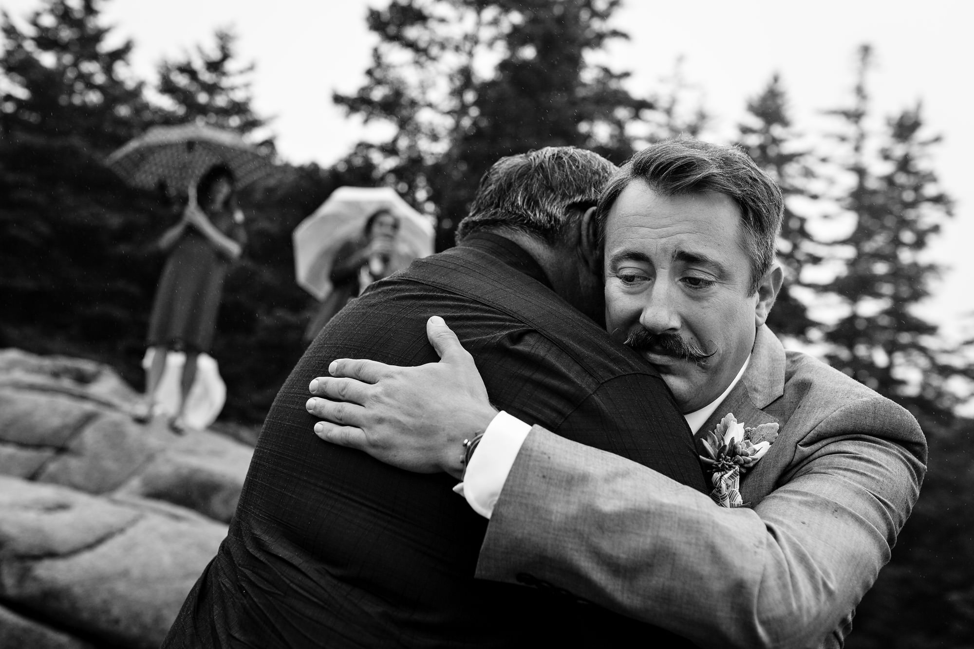 A groom hugs the father of the bride at his Acadia elopement