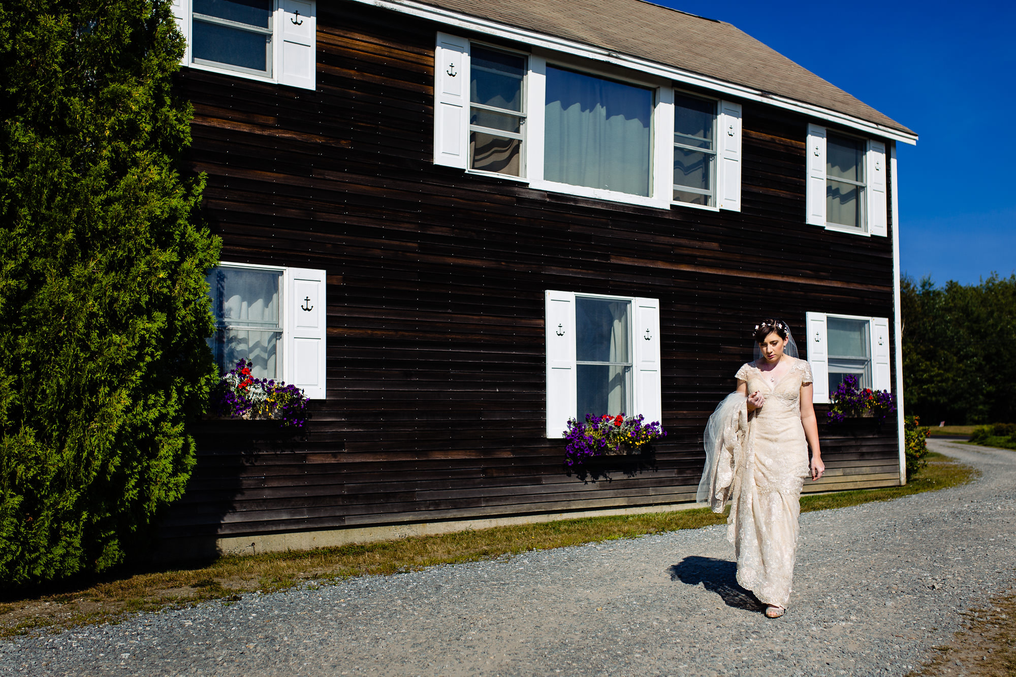 A bride walks to her first look at Pemaquid Point Lighthouse in Maine