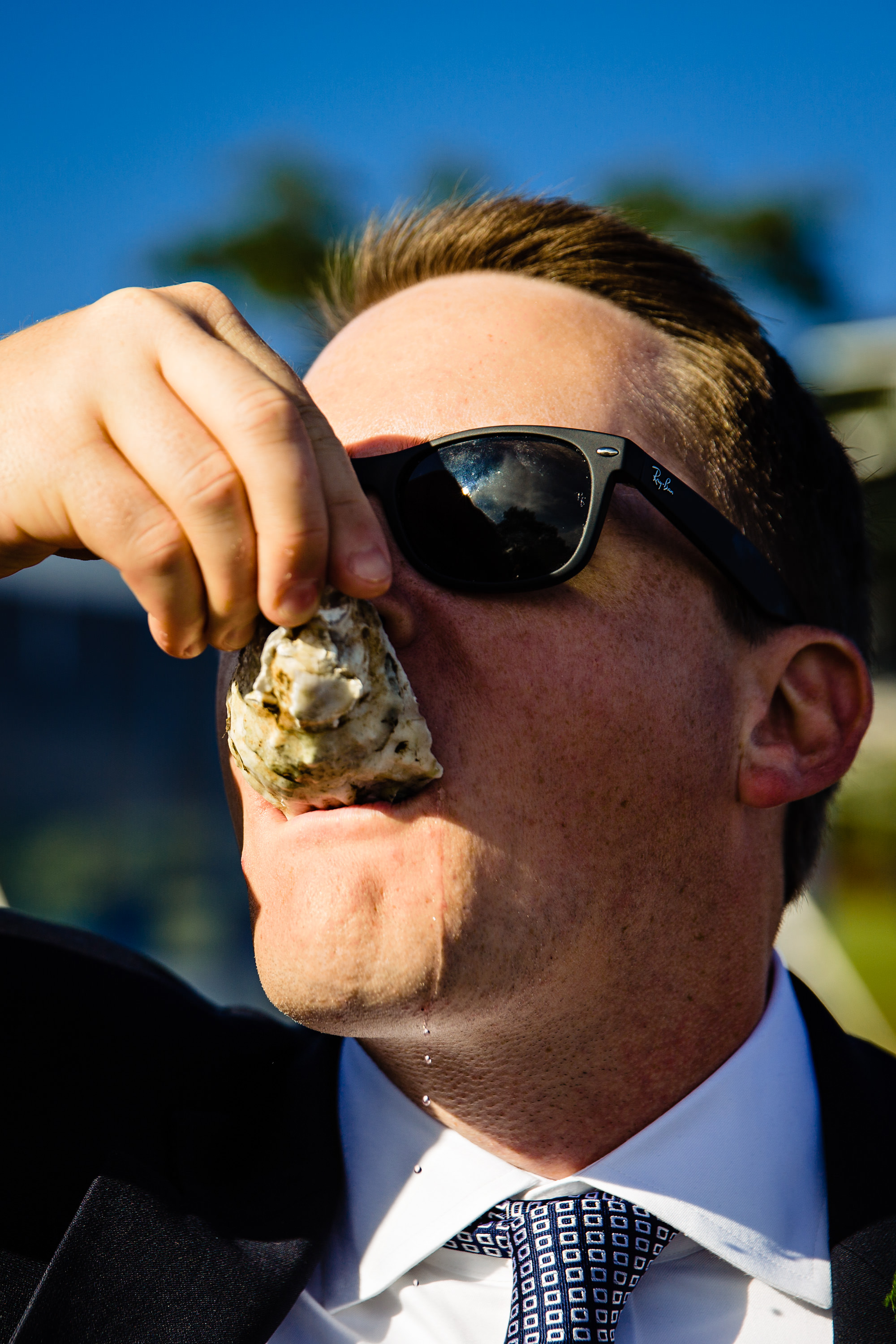 A guest eats an oyster and juice drips down his chin at a Maine wedding.