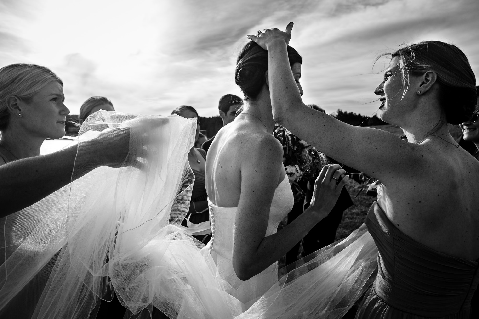 Bridesmaids help the bride with her veil and bustle at a Blue Hill Maine wedding
