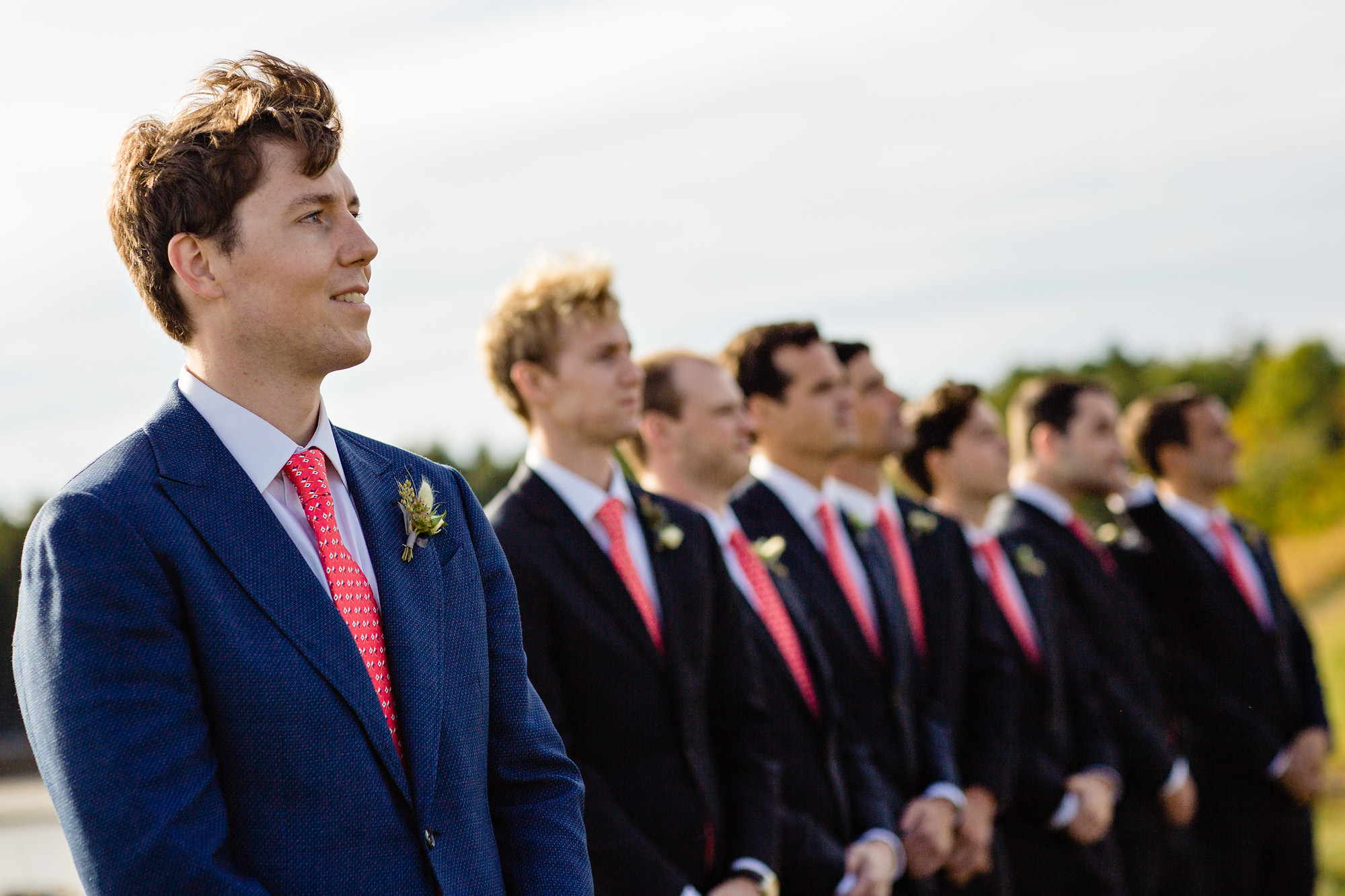 The groom watches the bride as she walks down the aisle at his Maine wedding