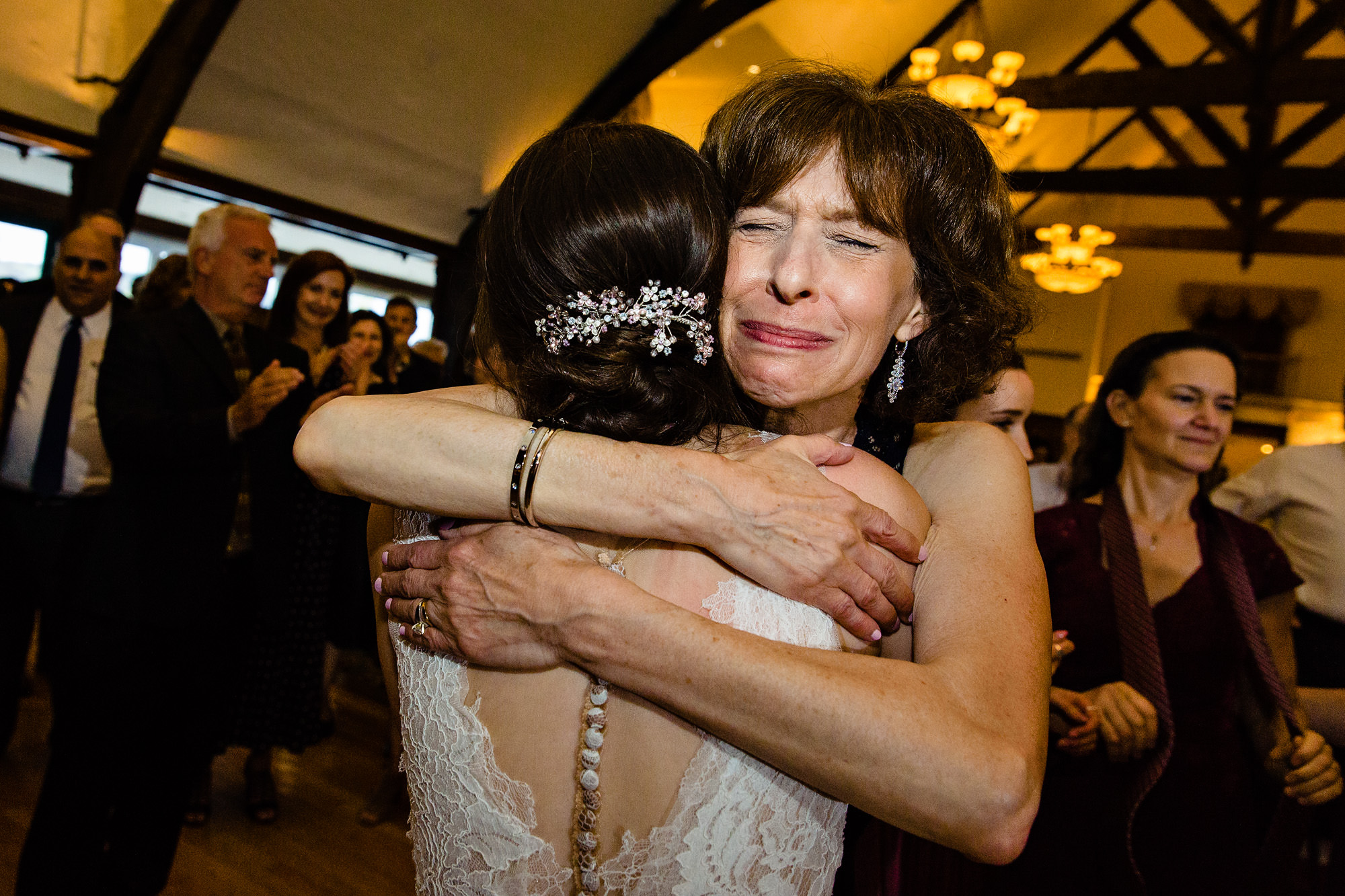 A candid photo of a mother of the bride hugging her daughter at a Maine wedding