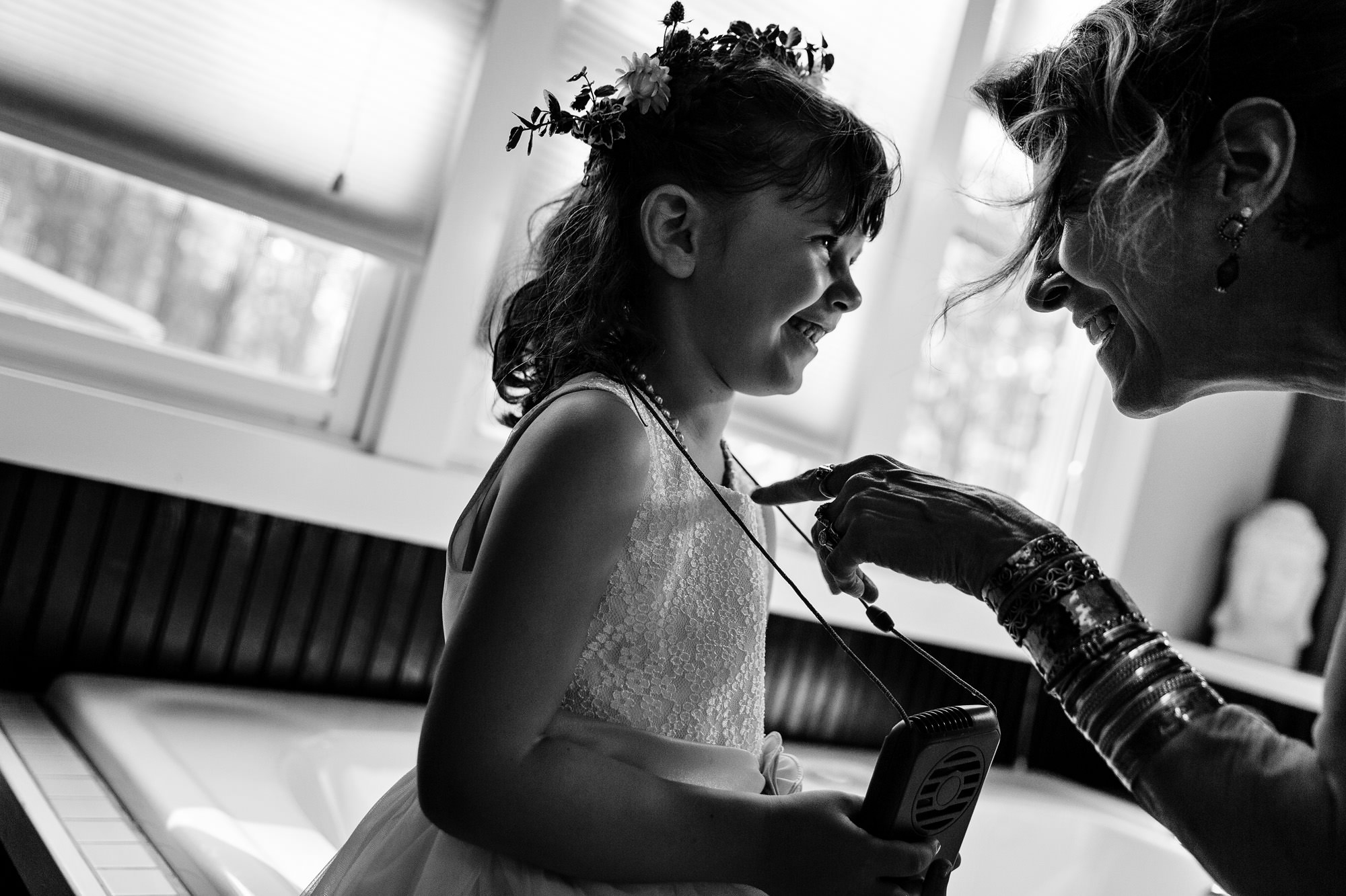 An adult pokes the flower girl's chest playfully at a western Maine wedding
