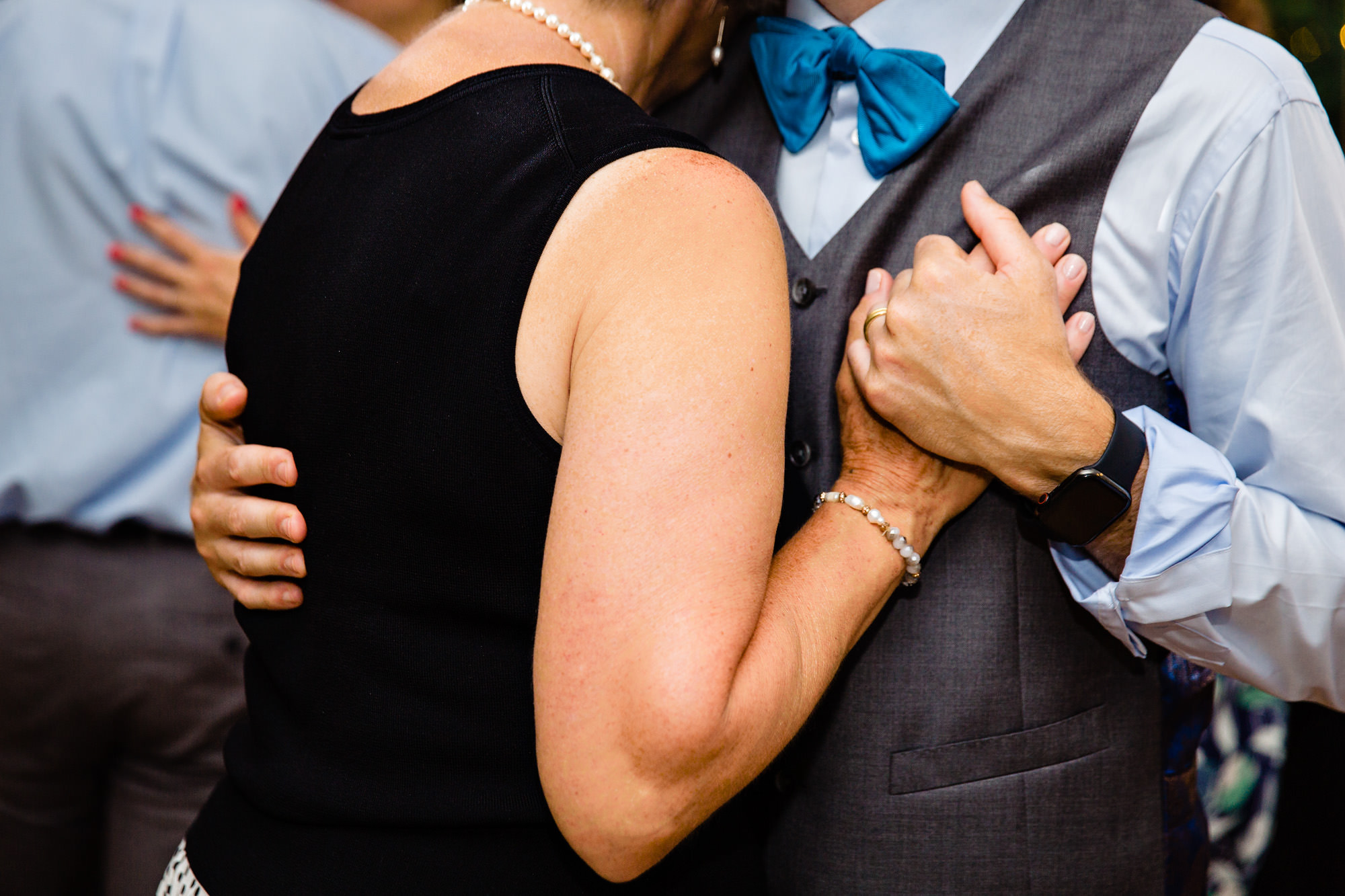 The groom holds his mother's hand at his wedding in Maine