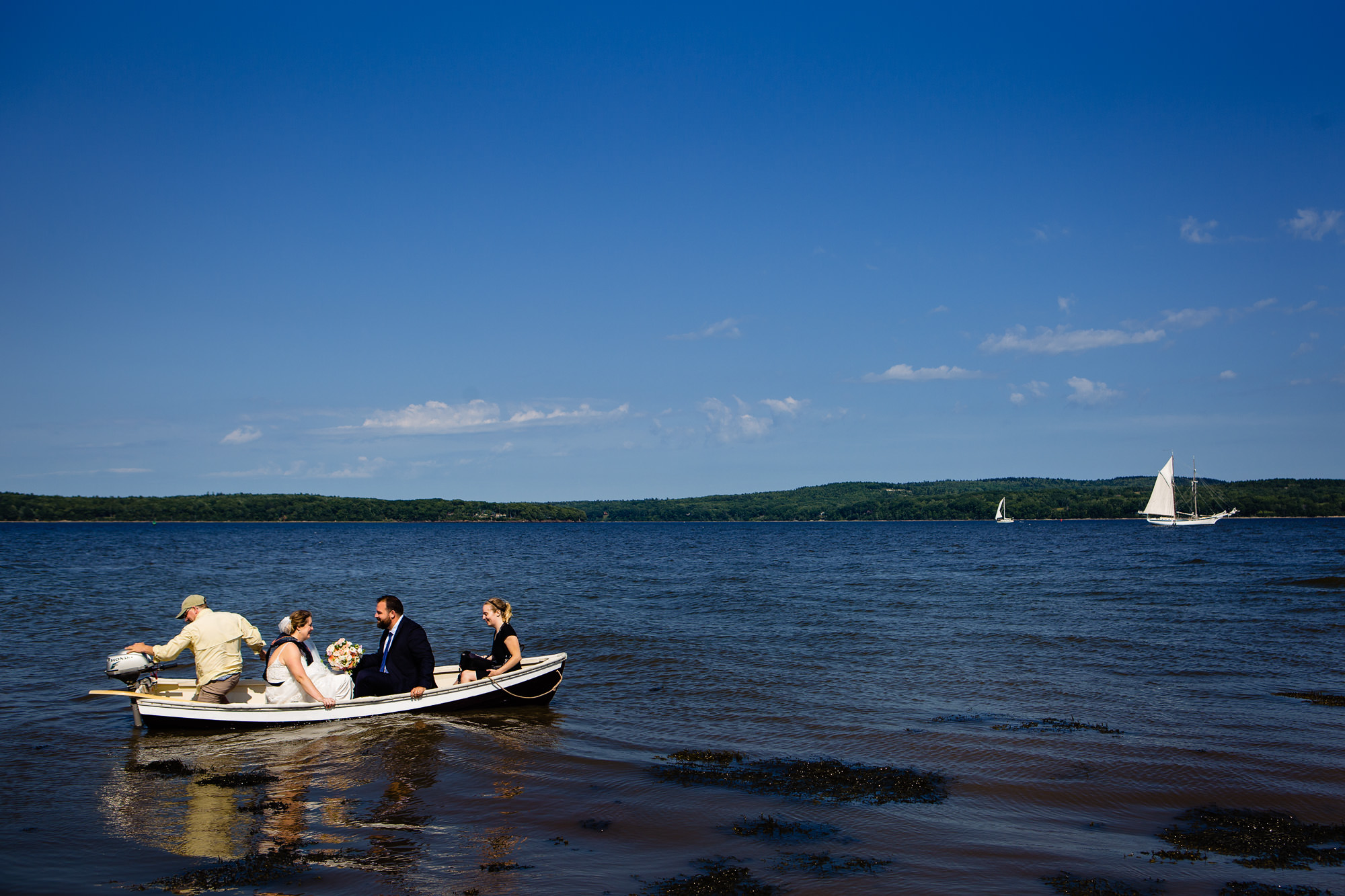 The bride and groom ride a dinghy to a sailboat at French's Point