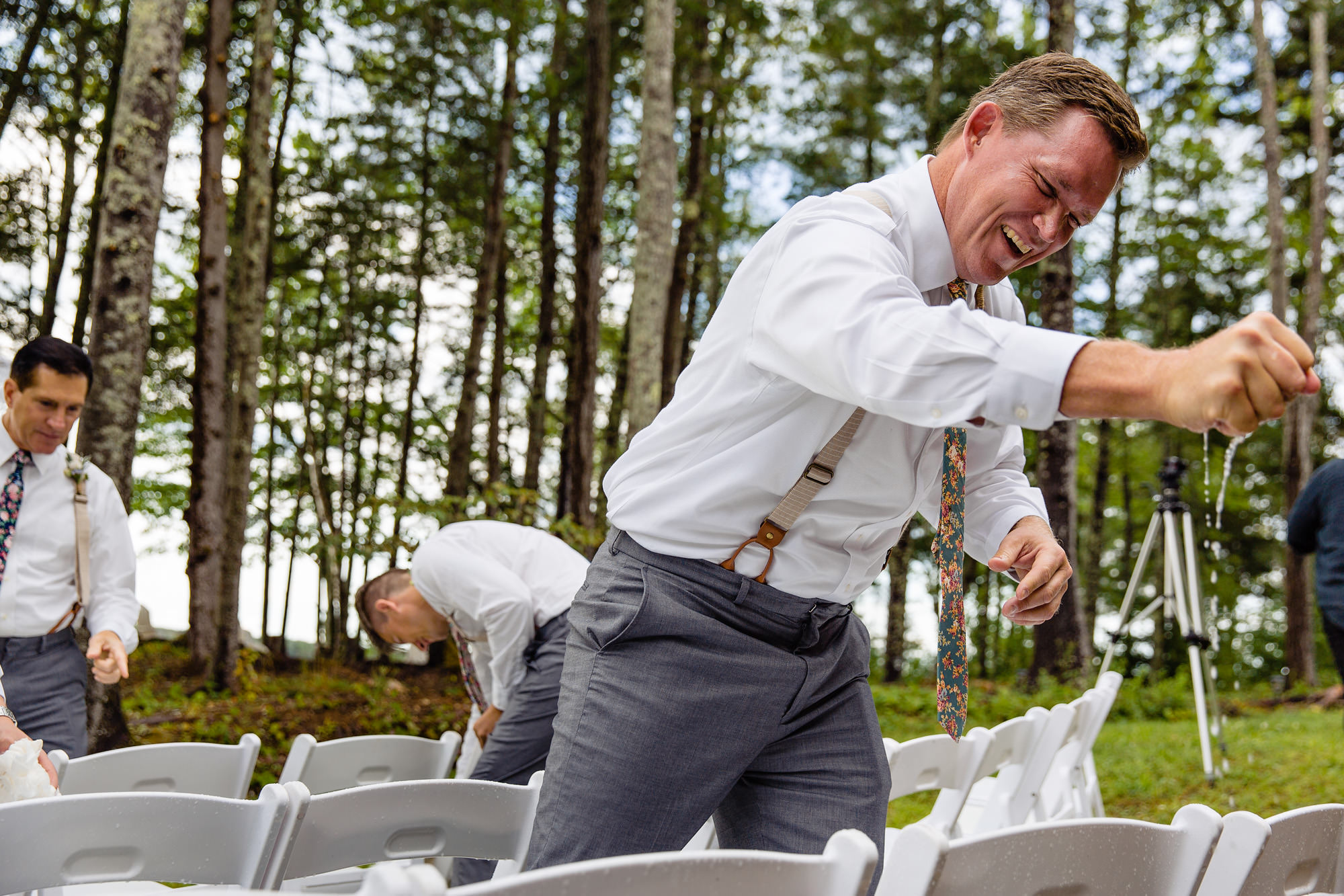 Groomsmen wipe down the ceremony chairs with paper towels after a rainstorm soaks them at a Maine wedding