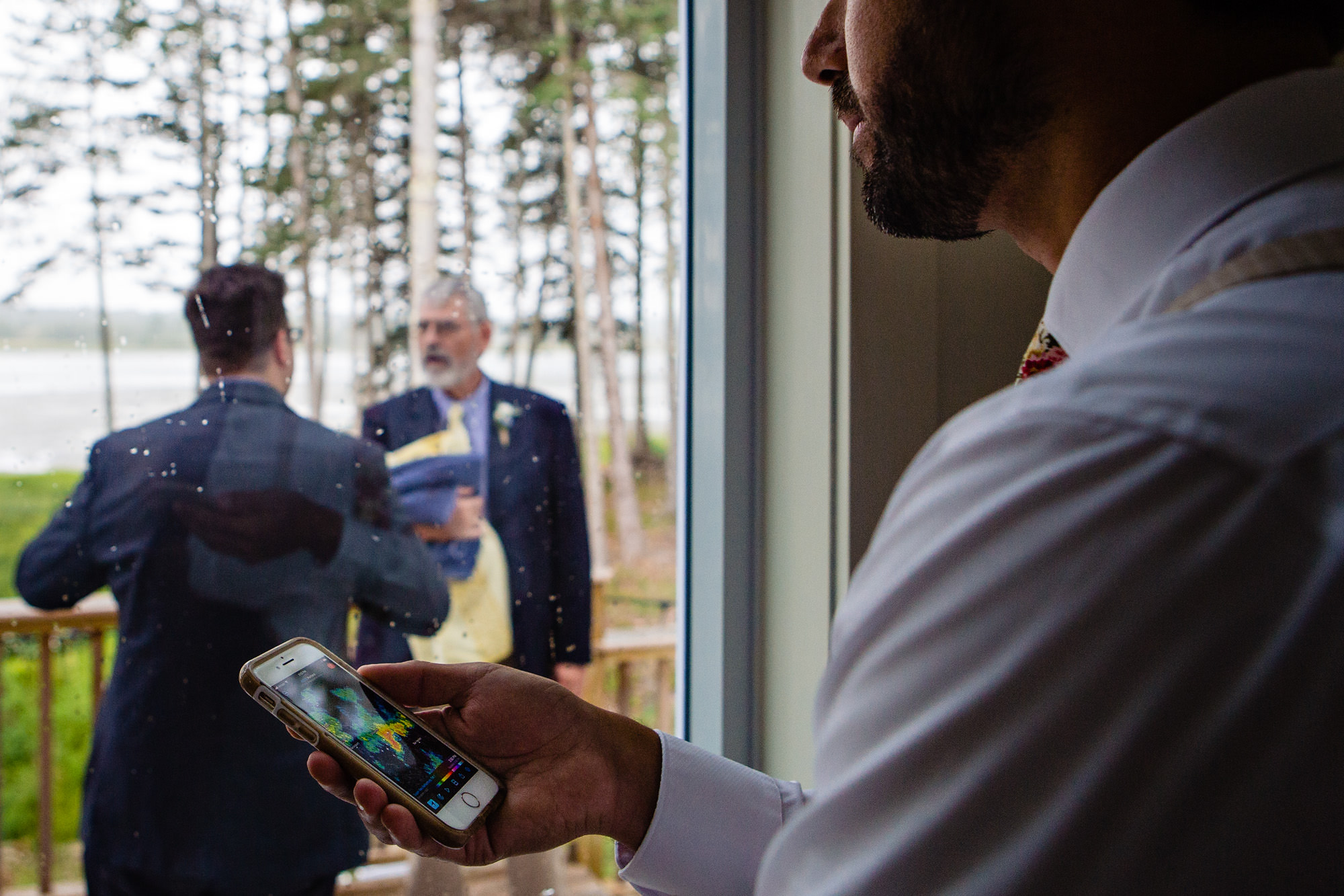 The groom checks the weather radar when it begins to hail at his Maine wedding