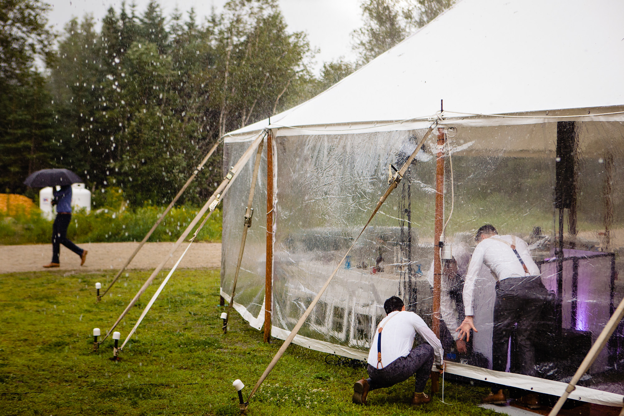 The groomsmen secure the tent during a hailstorm at a summer wedding in Maine