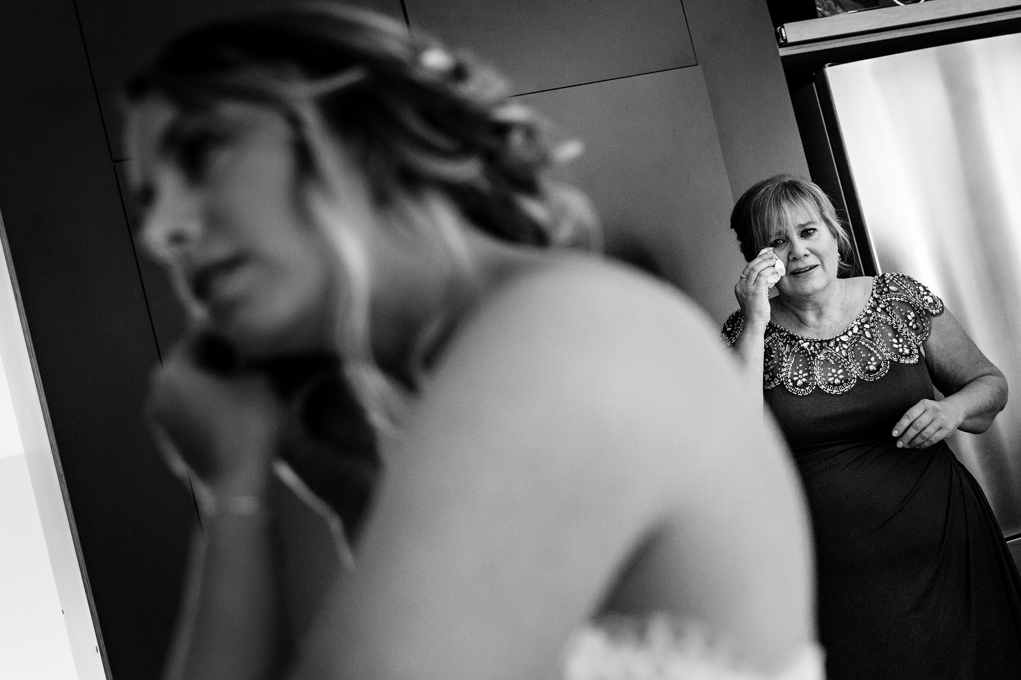 The mother of the bride cries as the bride puts on her jewelry for her midcoast Maine wedding