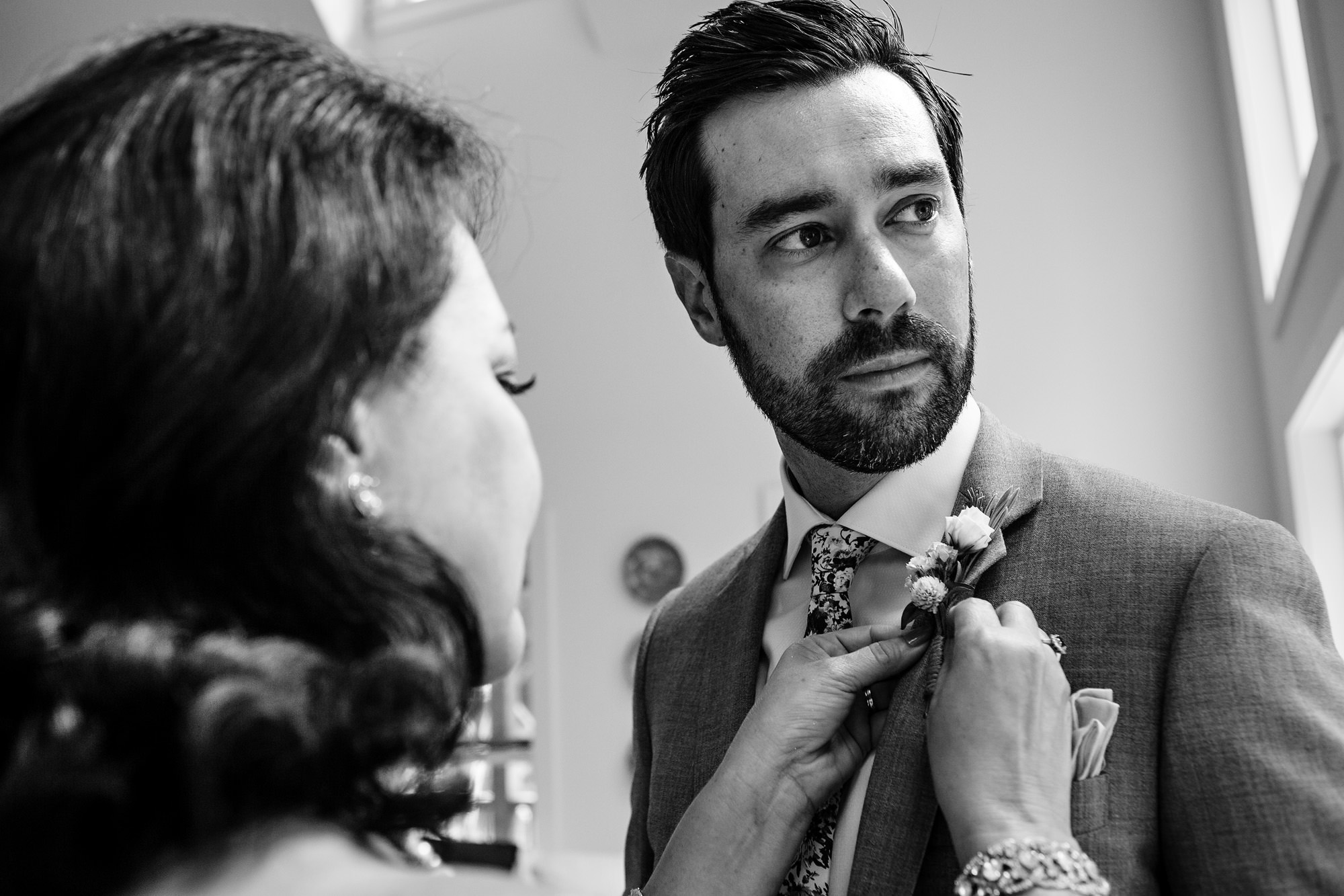 The mother of the groom helps her son get dressed at his private residence wedding
