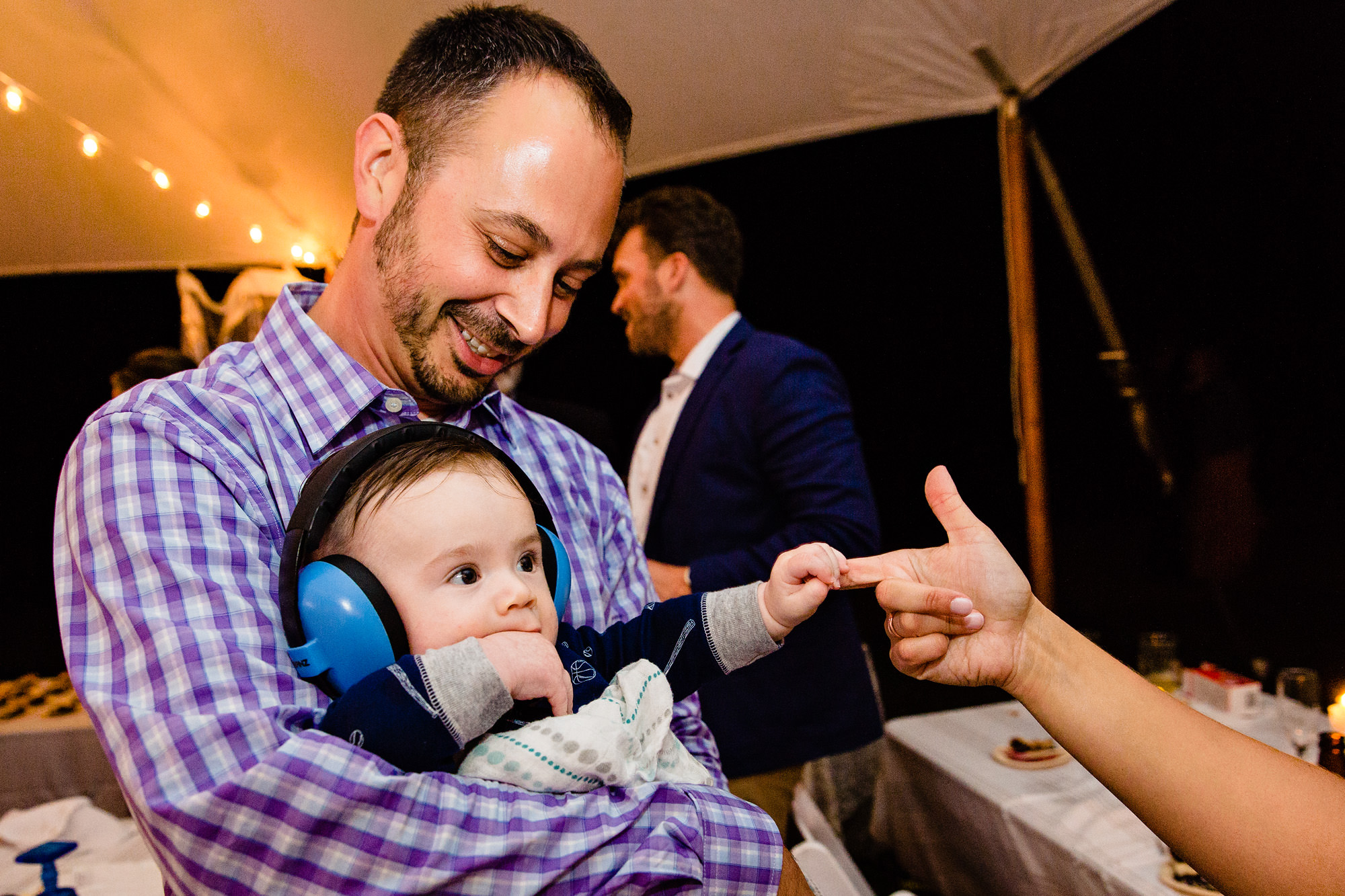 A baby at a wedding snatches an adult's hand during a Maine wedding