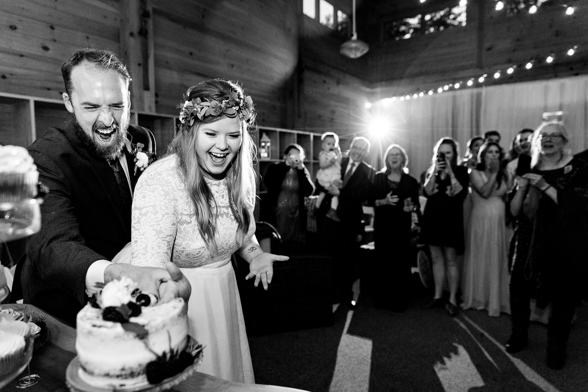A bride and groom cut the cake with their hands at their western Maine wedding