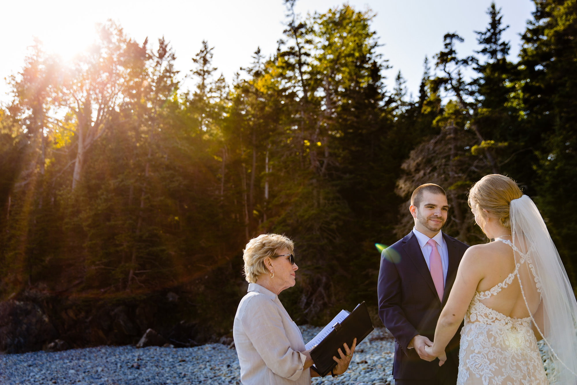 The groom looks at his bride during their wedding ceremony at Little Hunter's Beach in Acadia
