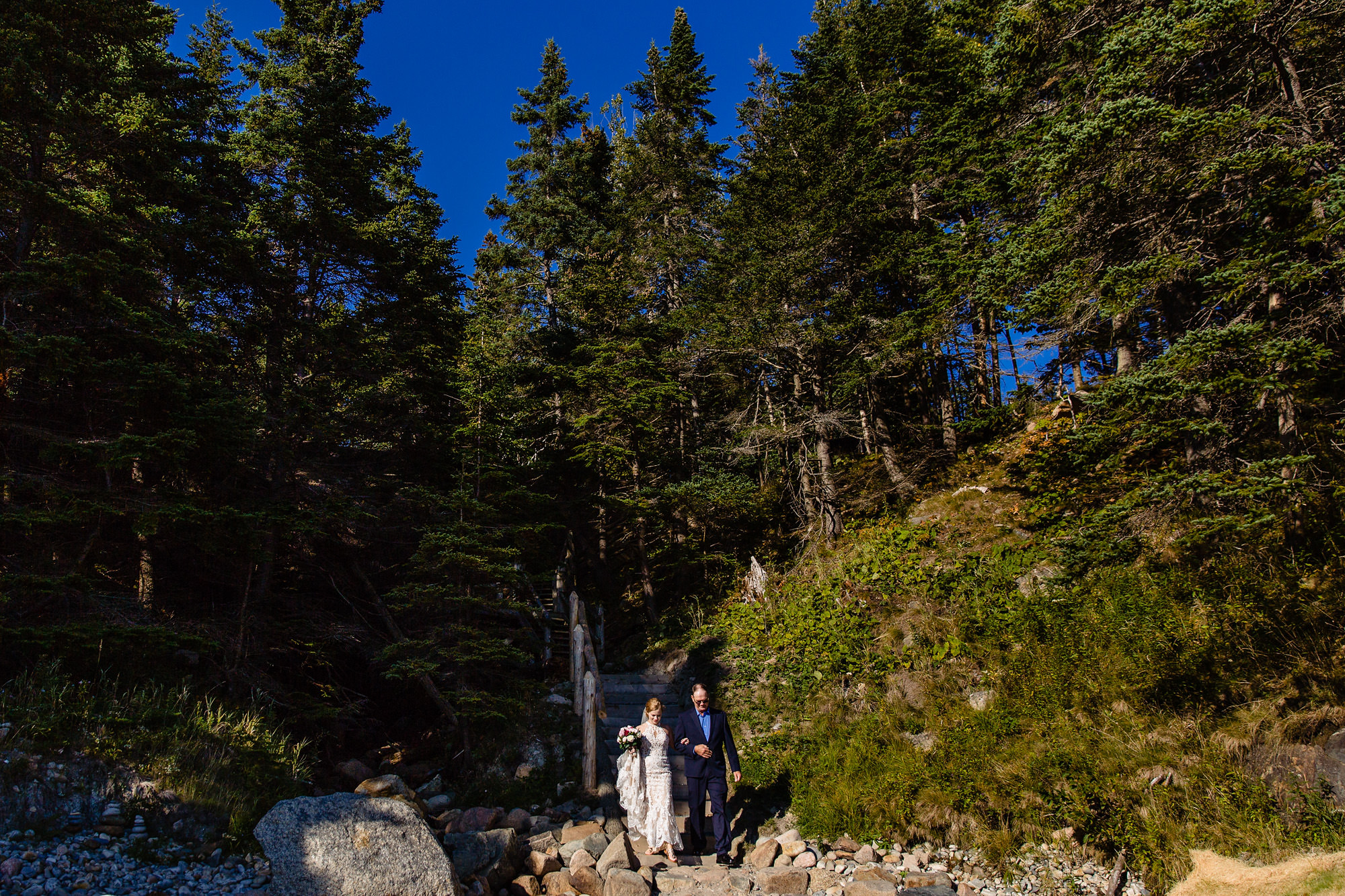 A bride walks with her father at Little Hunter's Beach in Acadia toward her wedding ceremony 