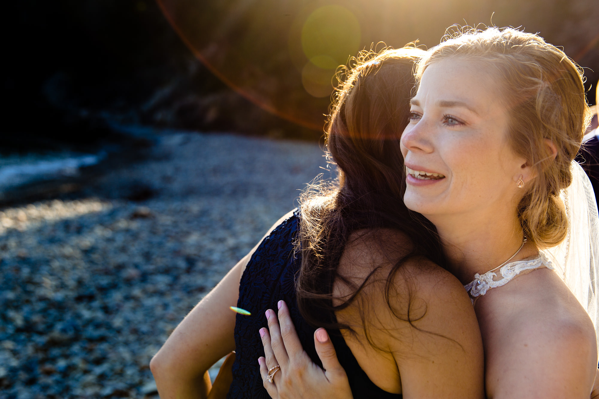 The bride hugs her sister at her elopement at Little Hunter's Beach in Acadia