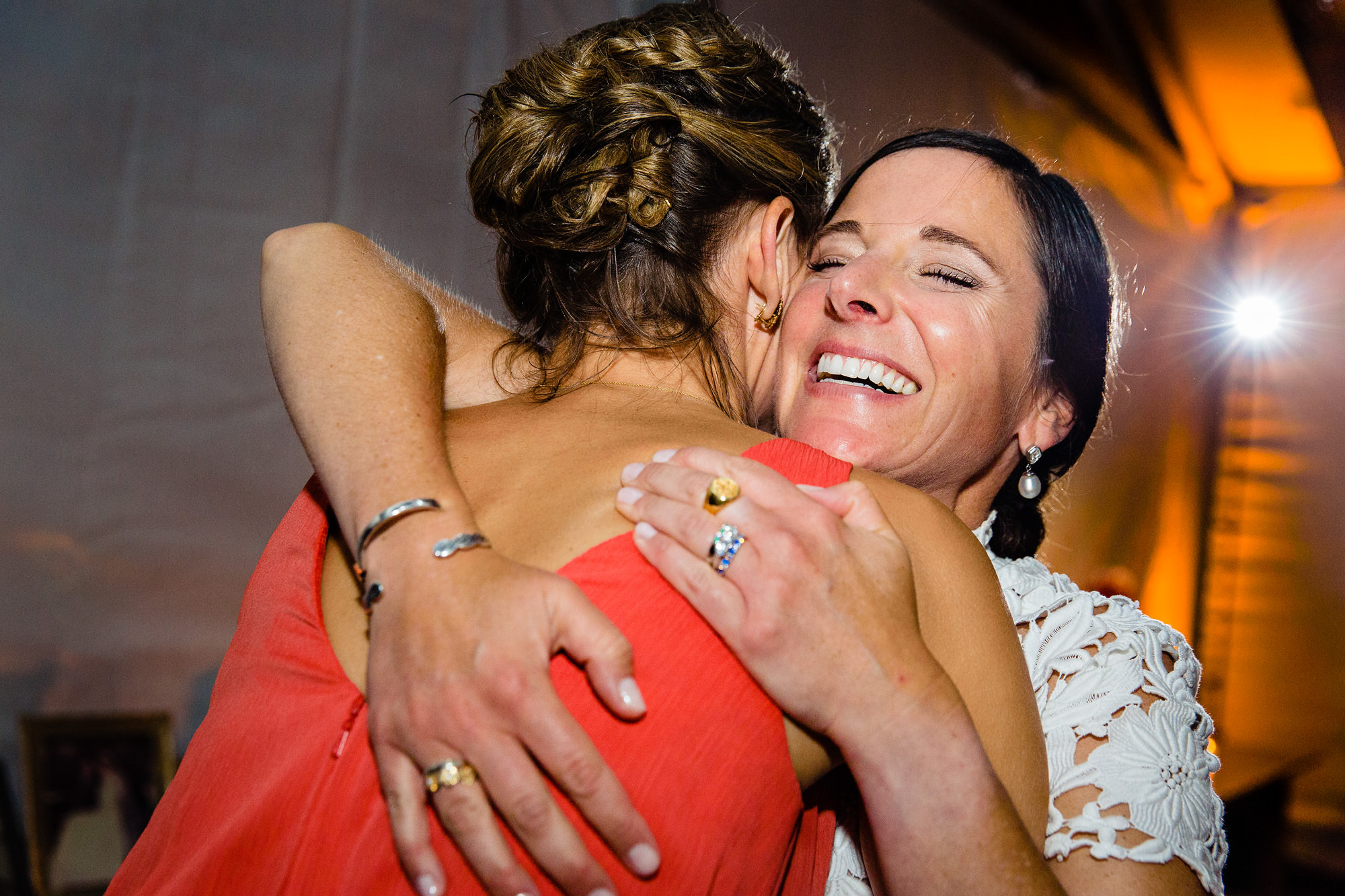 The bride hugs her bridesmaid at a Maine wedding