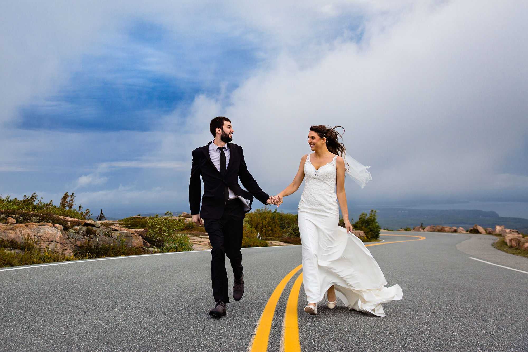A bride and groom run on top of Cadillac Mountain in Acadia National Park