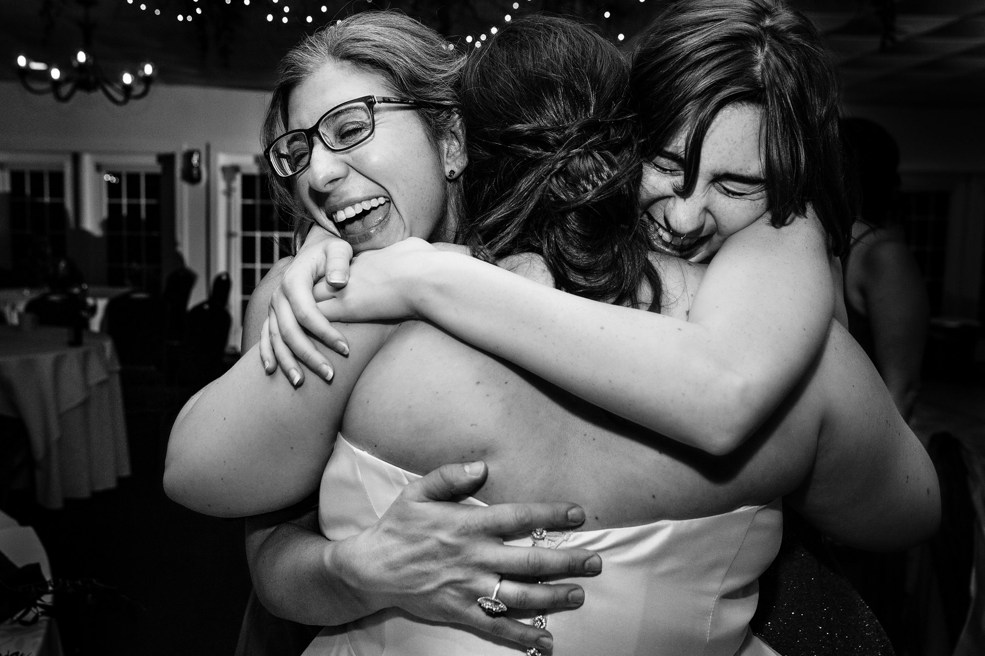 Two of the bride's best friends hug the bride at the end of her wedding reception in Maine