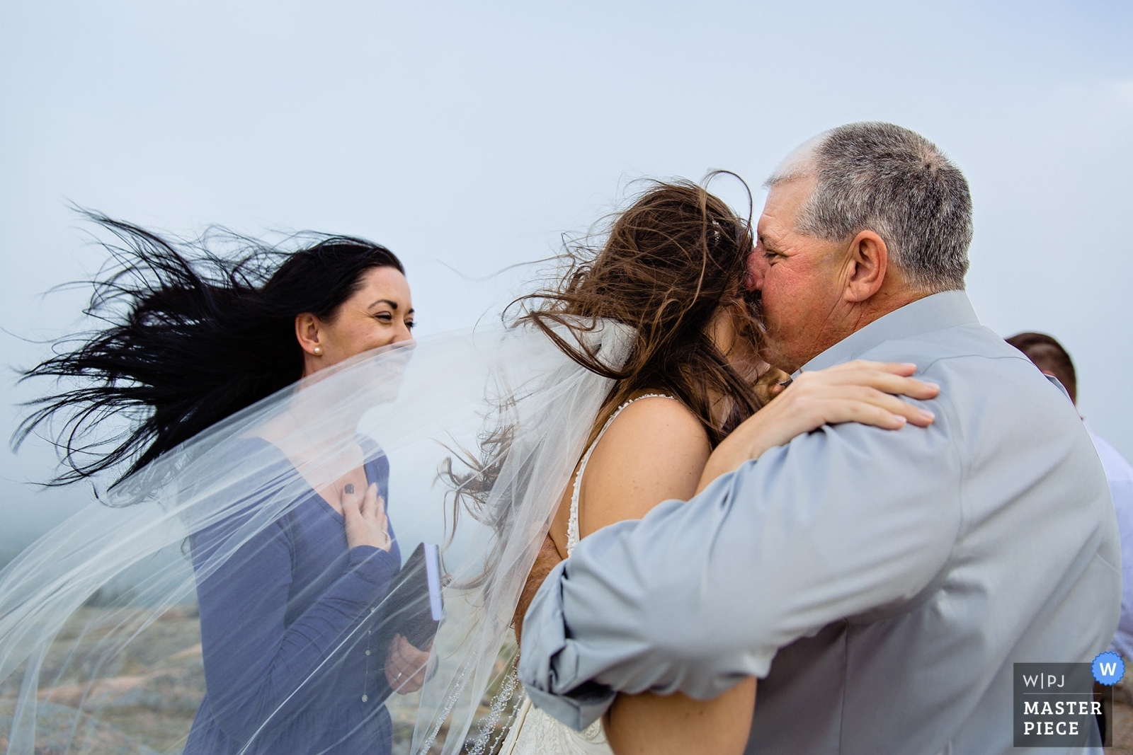 The bride's father kisses her on the cheek during her Acadia National Park elopement