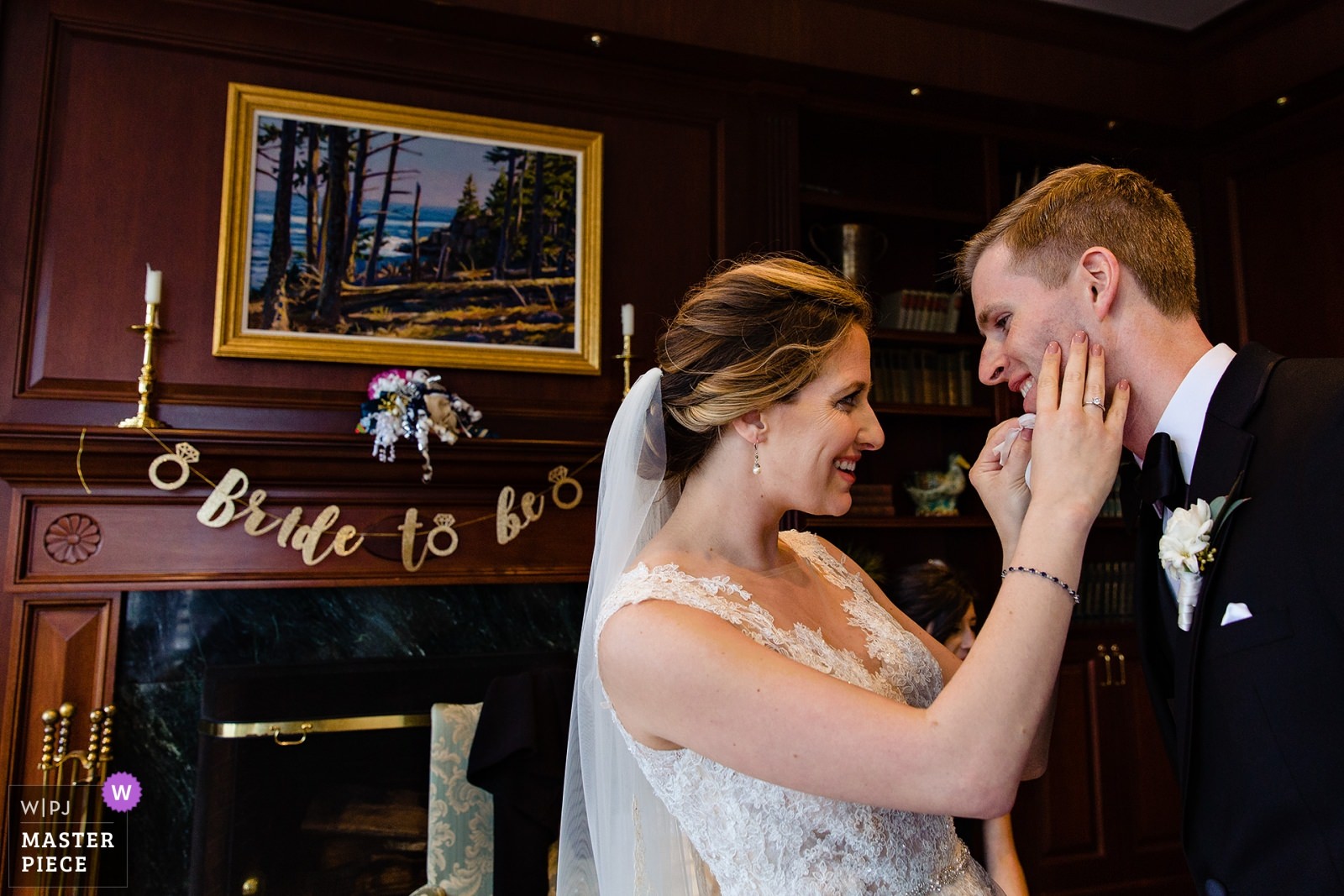 A bride cleans lipstick off of her groom to be's face at her Camden Maine wedding