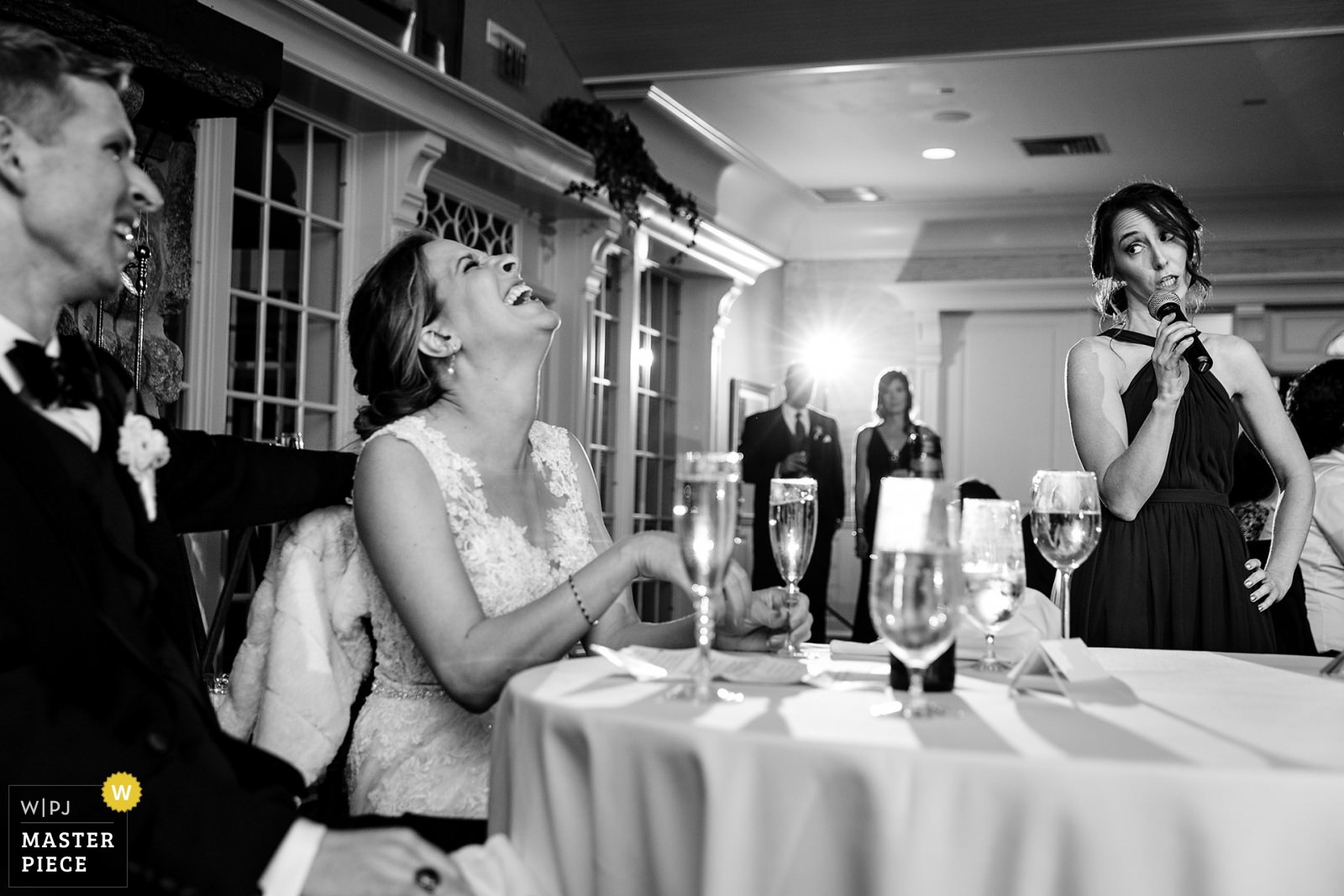 A bride and groom laugh at the maid of honor's toast at a Camden Maine wedding